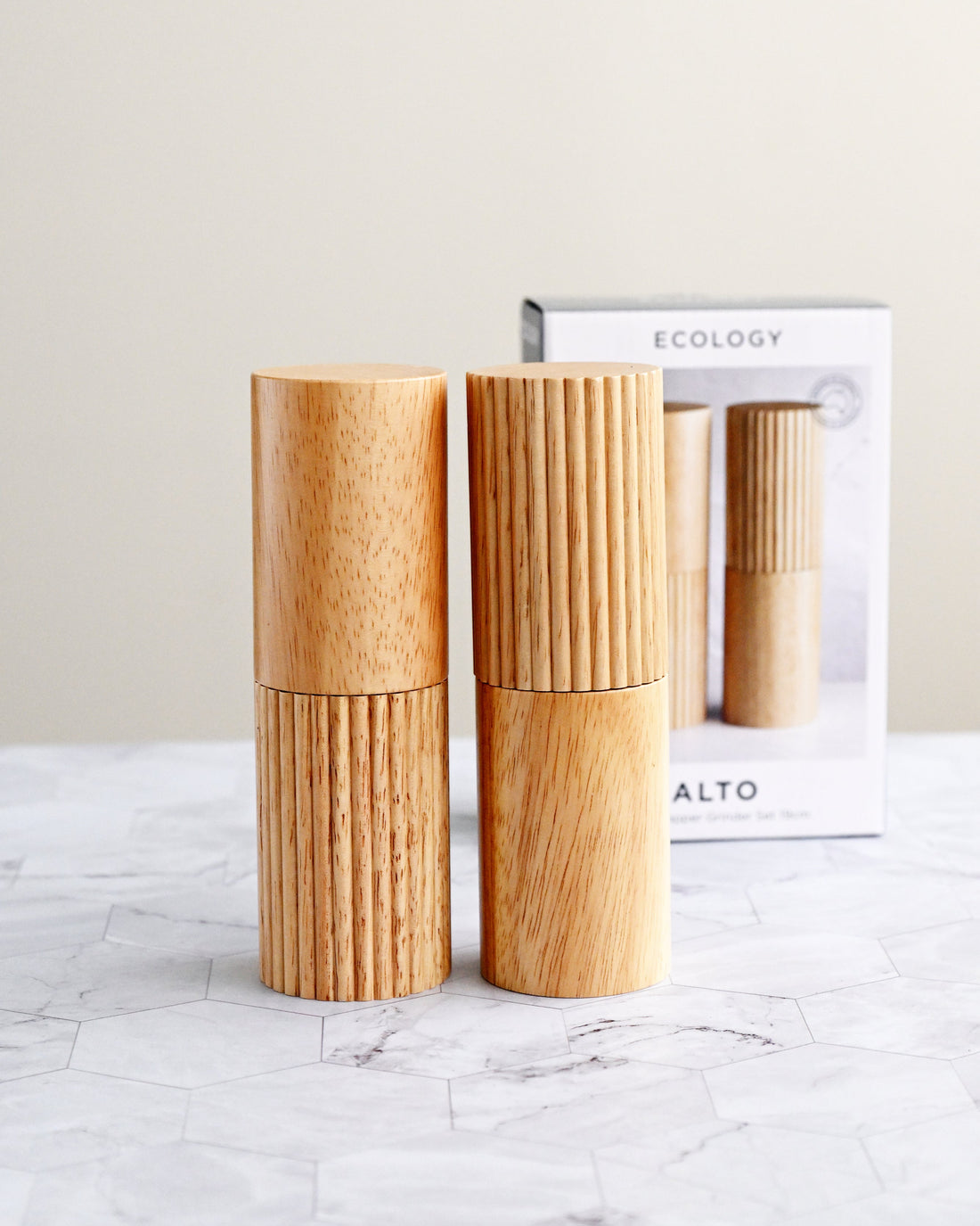 Wooden salt and pepper shakers on a marble surface with a neutral background