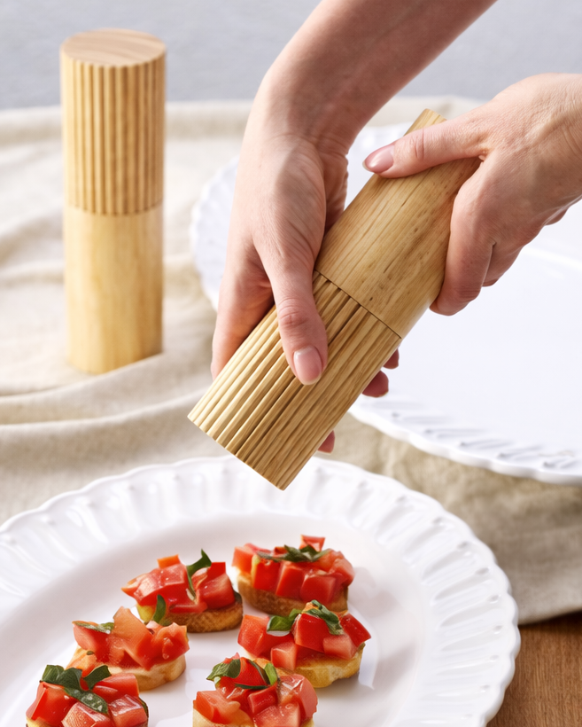 Person using a wooden pasta shaper to make small pasta shapes on a plate with appetizers.