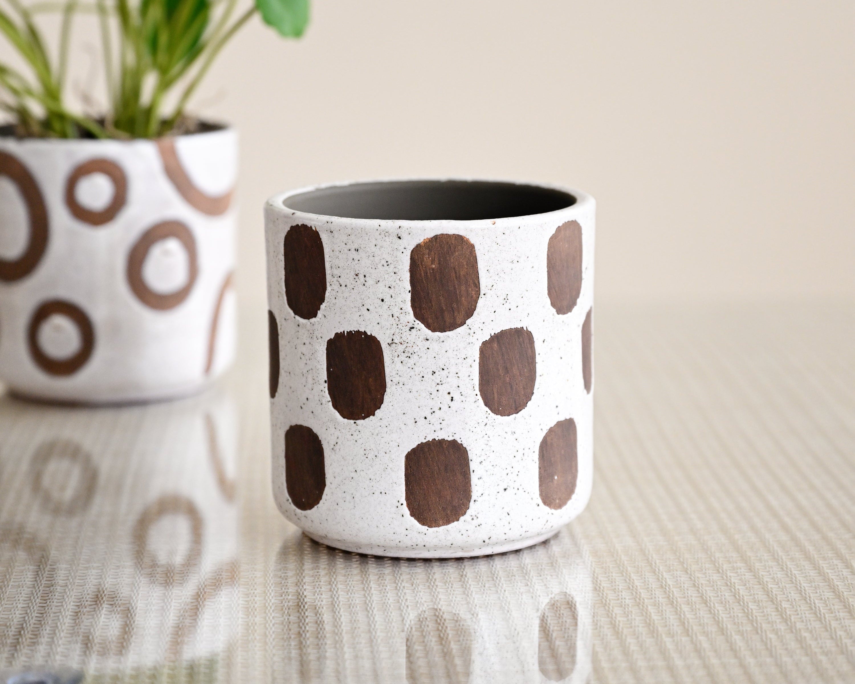 Ceramic planters with brown circular patterns on a neutral background