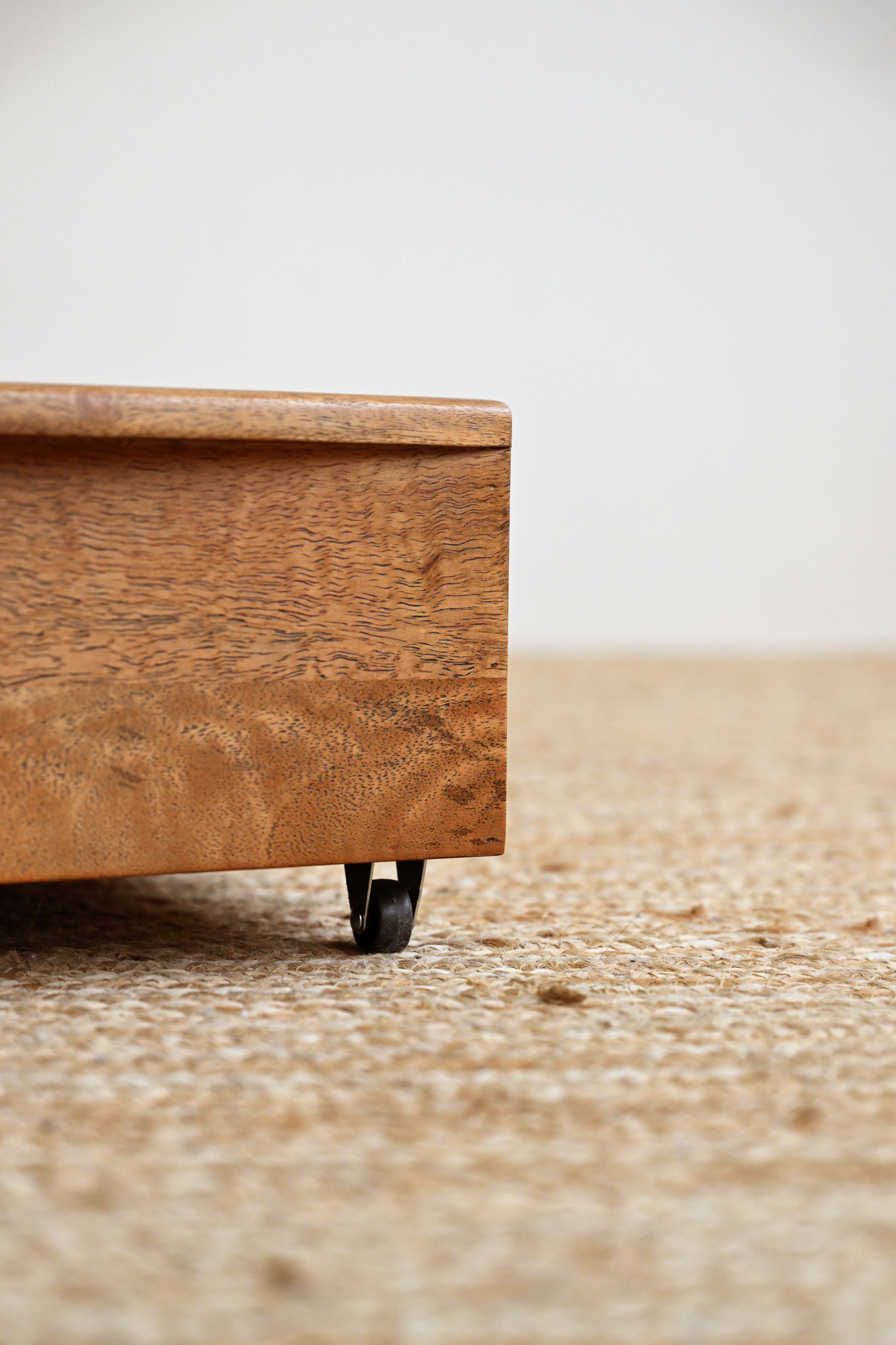 Wooden drawer with wheels on a textured surface