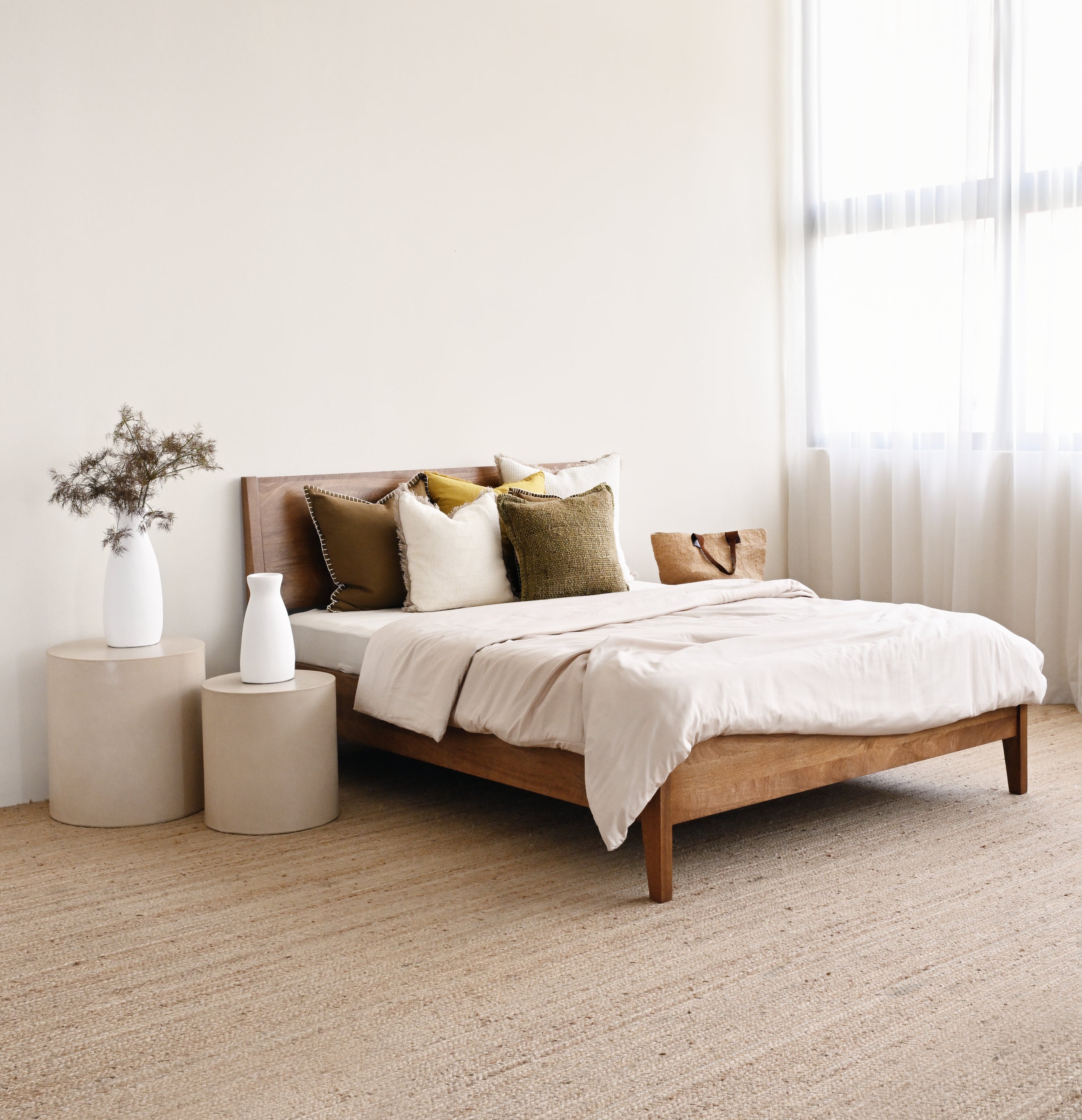 Bedroom with a wooden bed, beige bedding, and side tables.