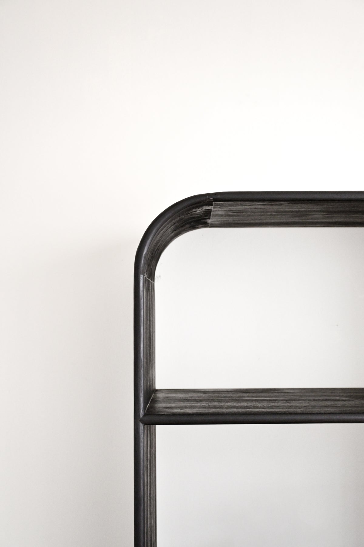 Close-up of a dark charcoal gray metal shelving unit corner against a plain white background.