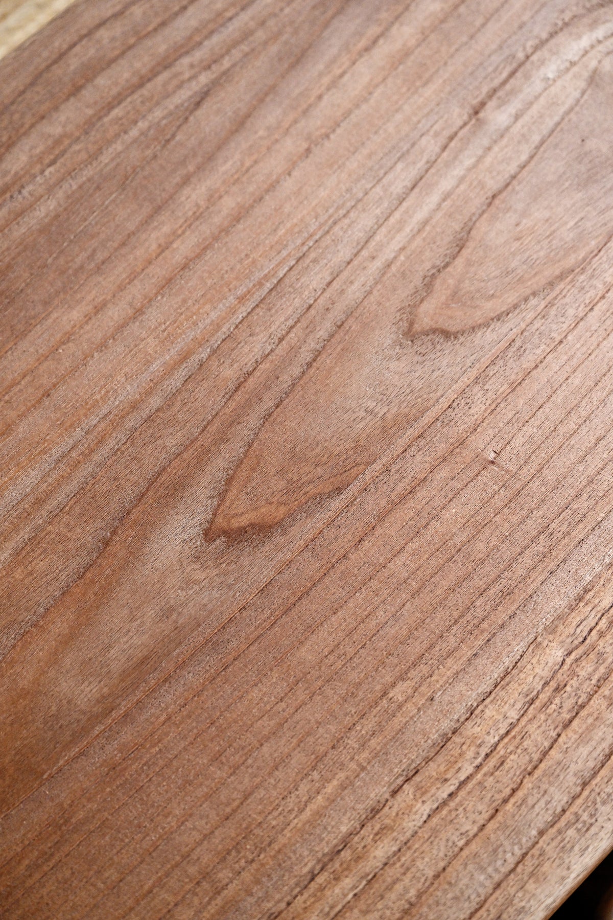 A close-up view of a medium brown wood grain surface with visible natural patterns and texture.