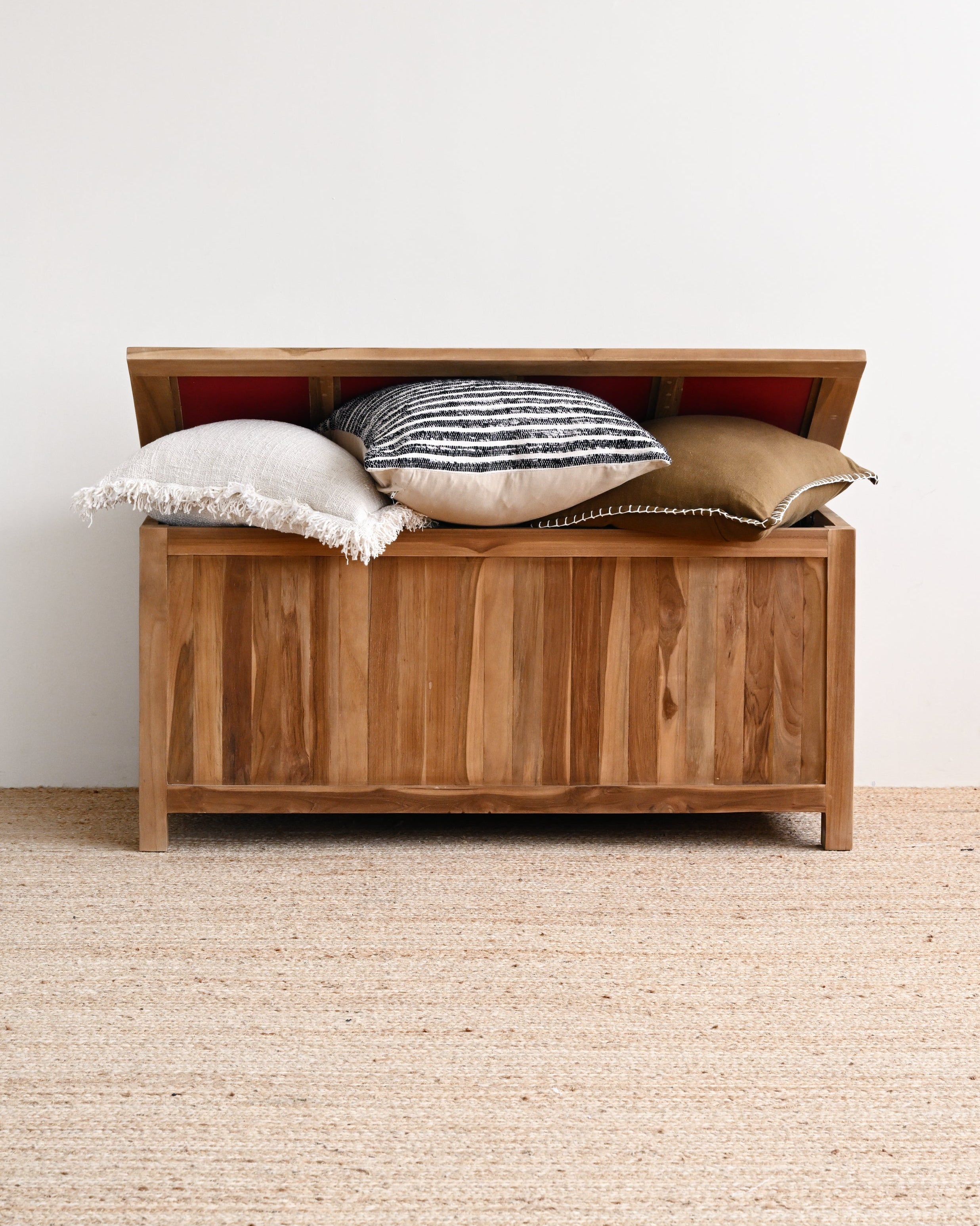 Wooden storage bench with pillows on a neutral background