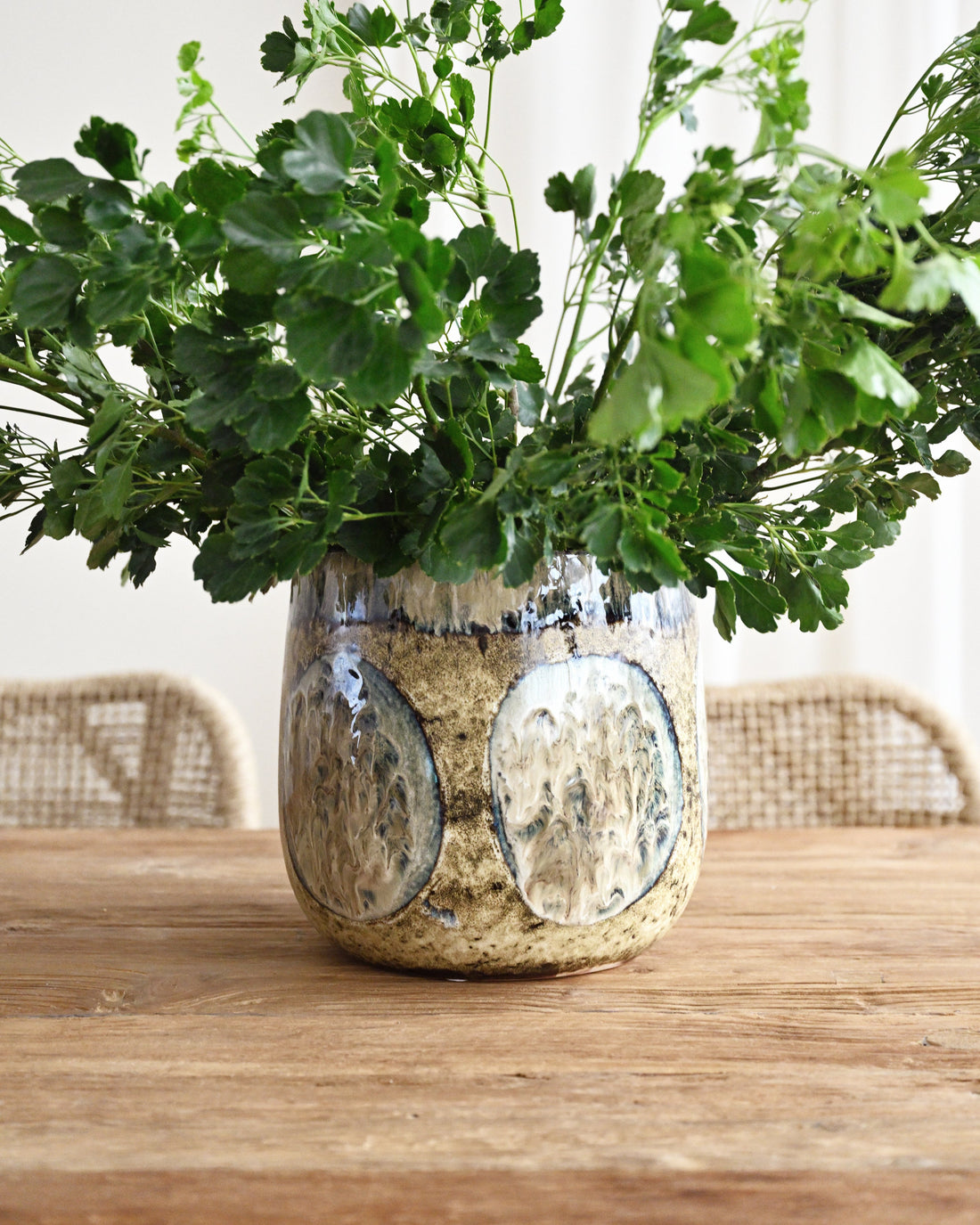Decorative vase with green foliage on a wooden table