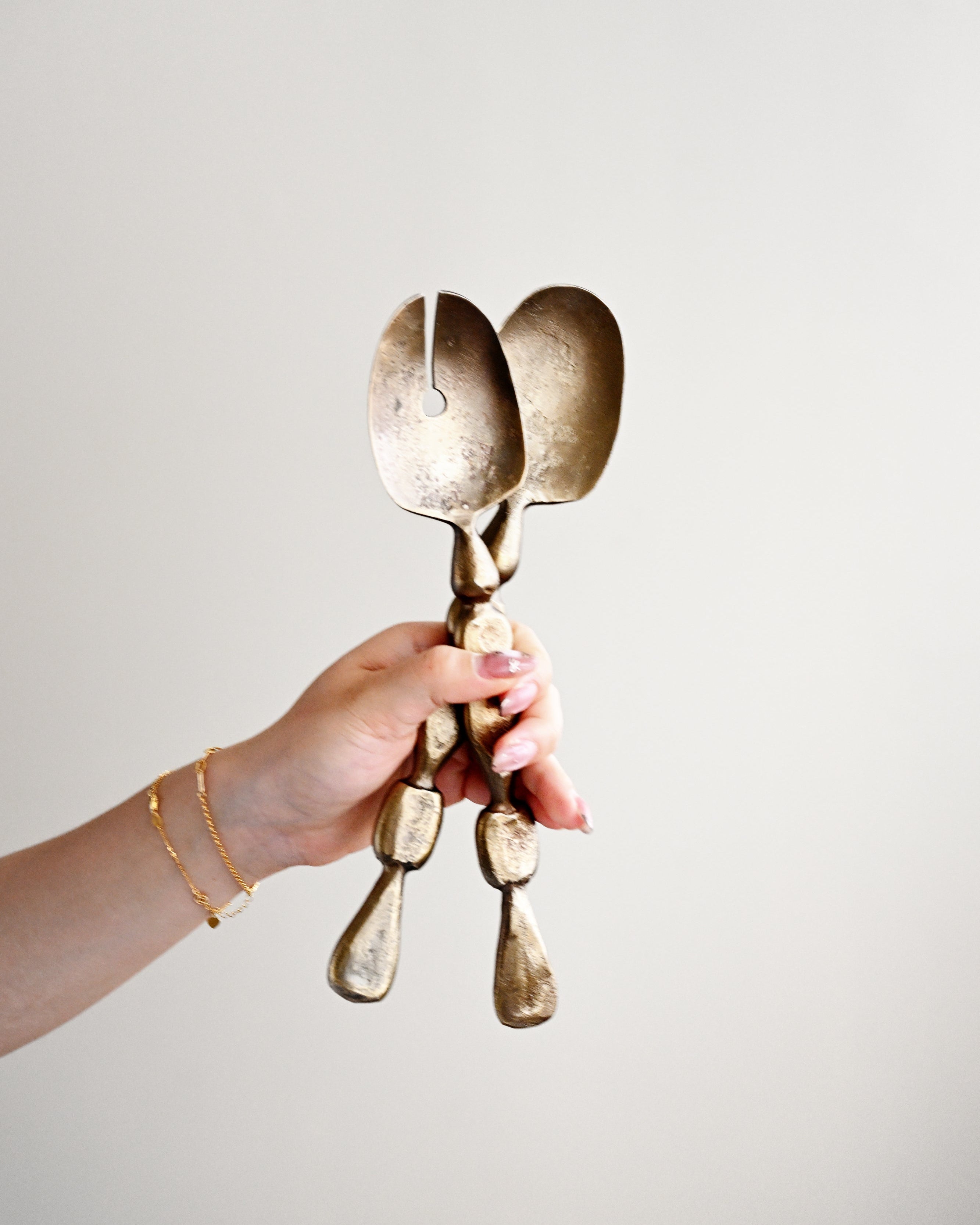 Person holding a unique gold spoon sculpture against a plain background