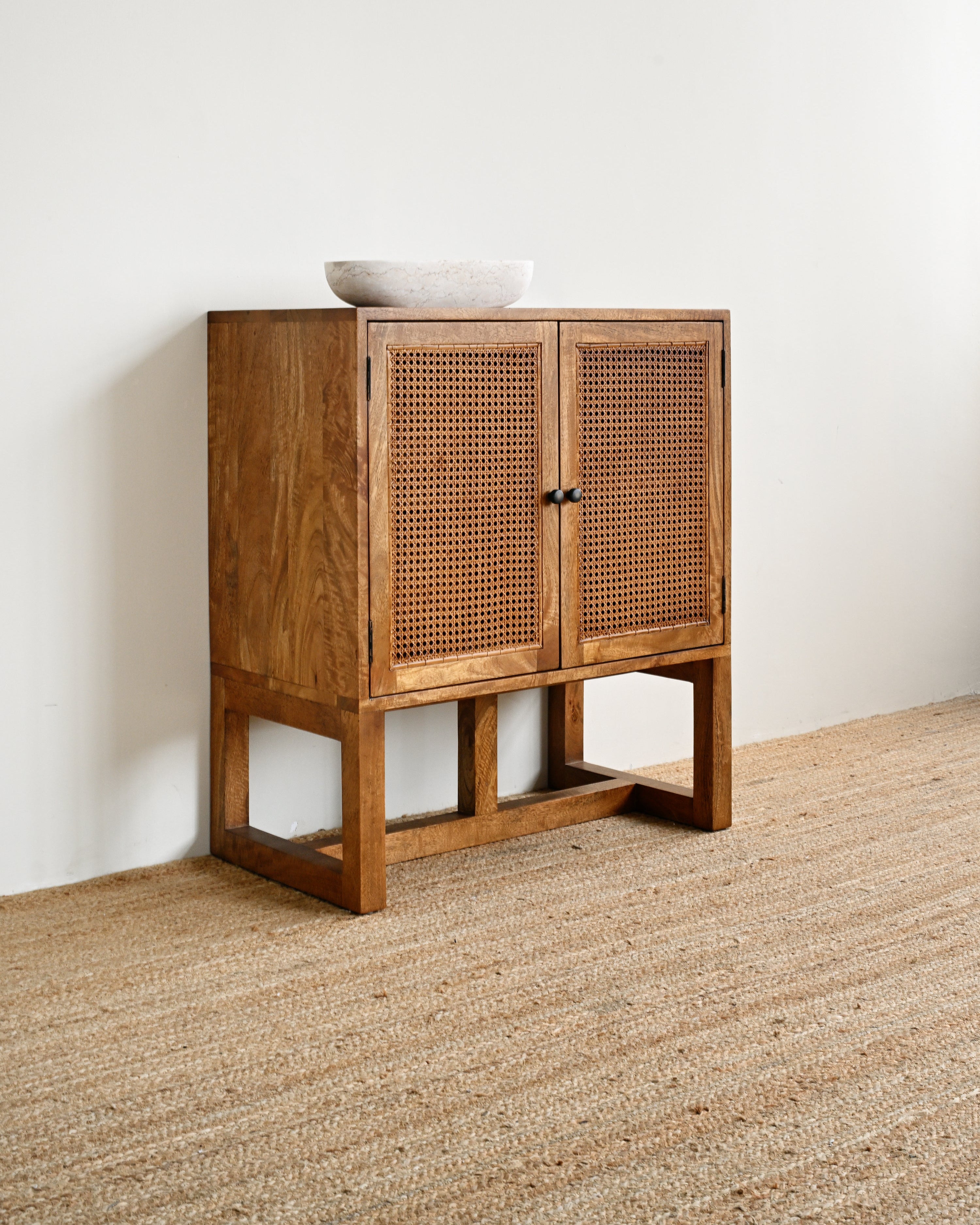 Wooden cabinet with wicker doors on a neutral background