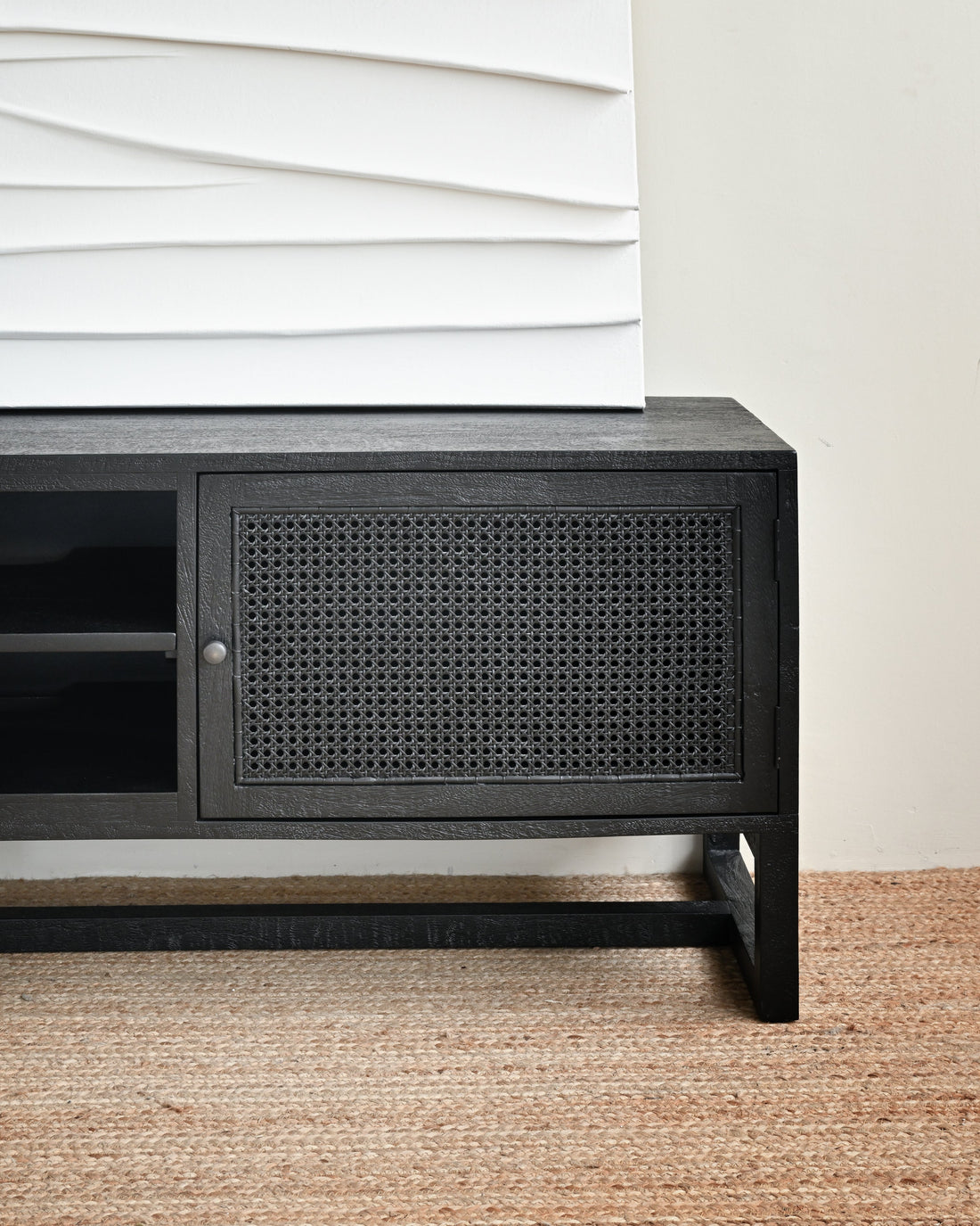 Black cabinet with wicker door on a beige carpet