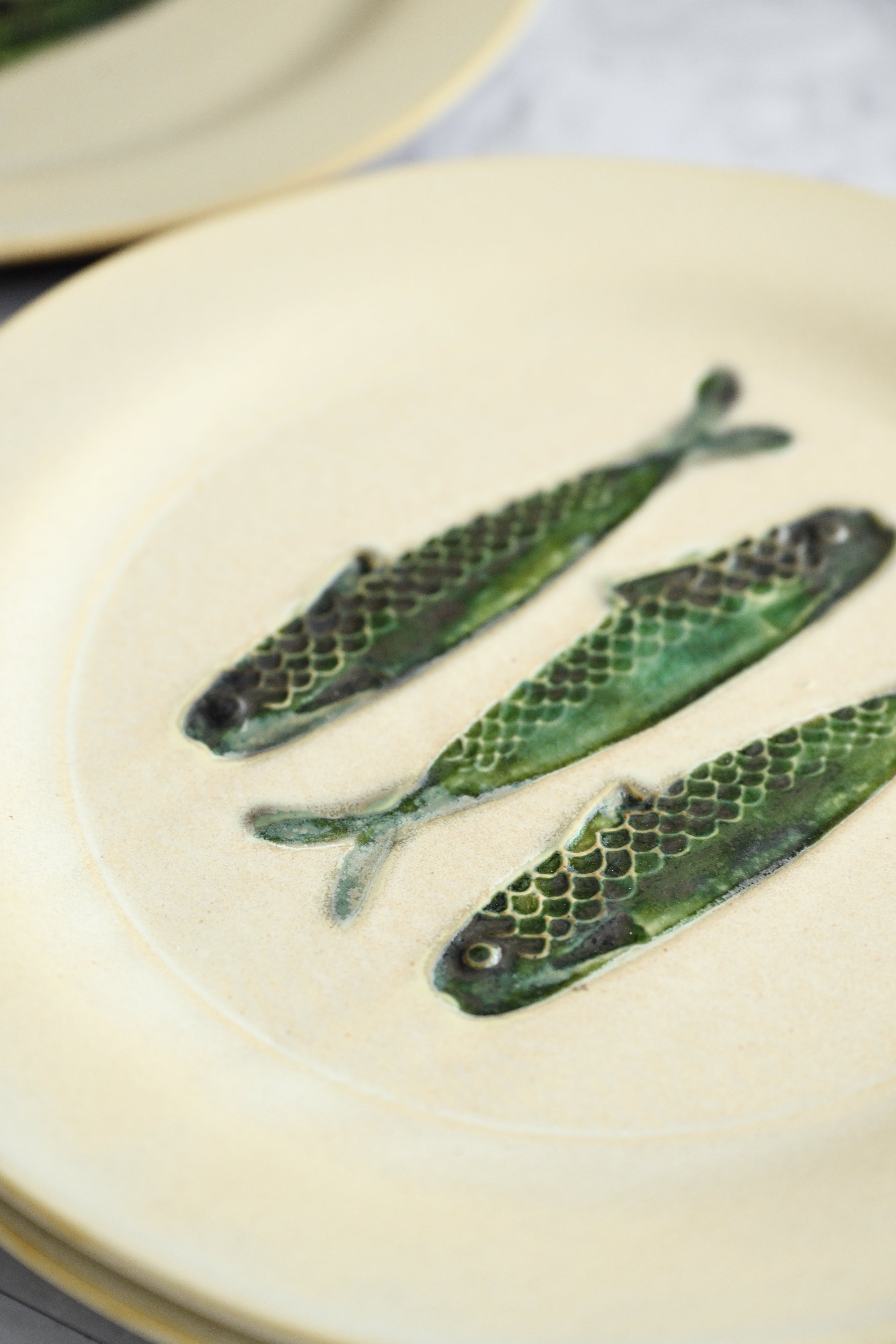 Three fish-shaped green cookies on a white plate