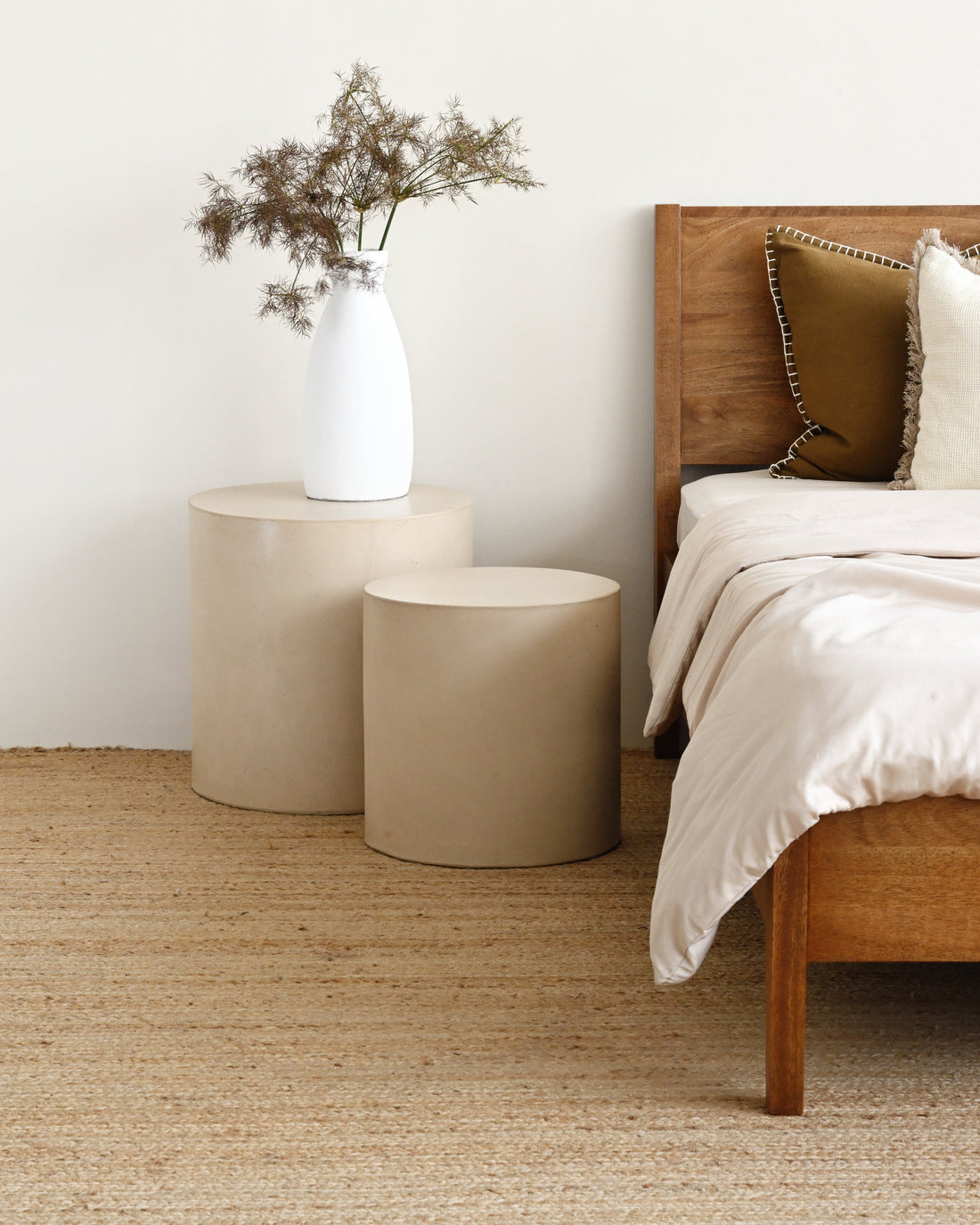 Bedroom with wooden bed, beige rug, and side tables.