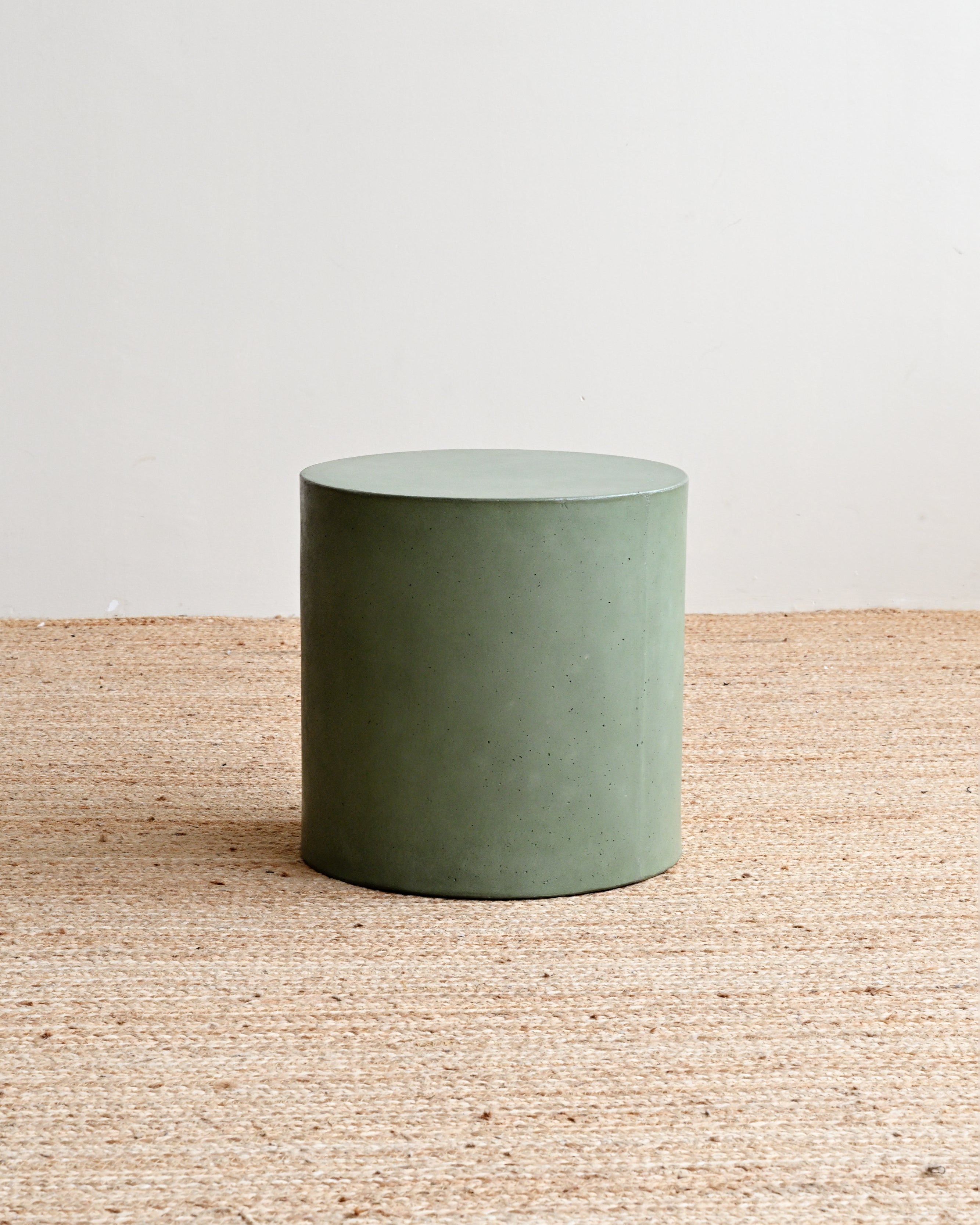 Green cylindrical object on a textured surface with a light background