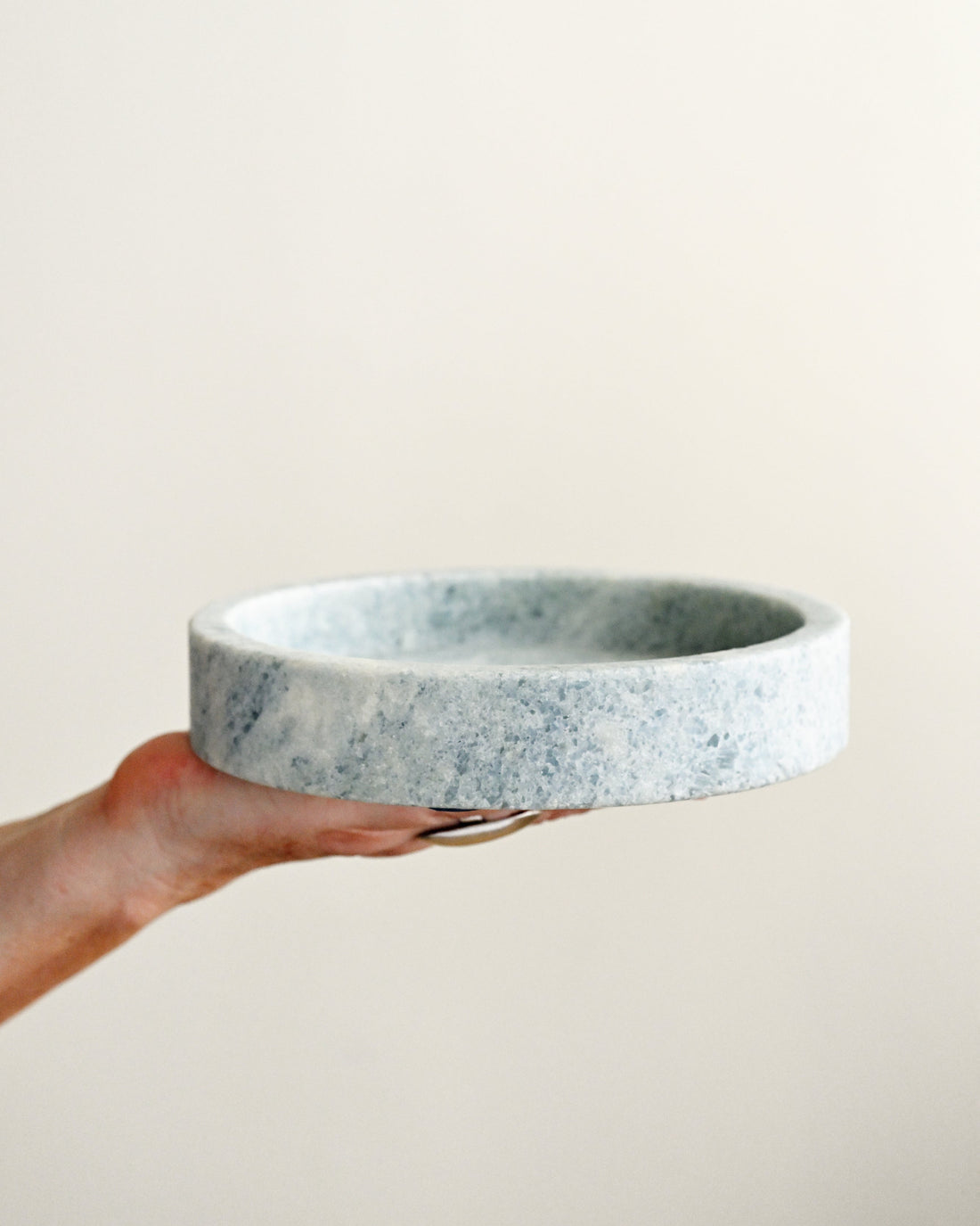 Hand holding a marble-patterned ceramic bowl against a plain background