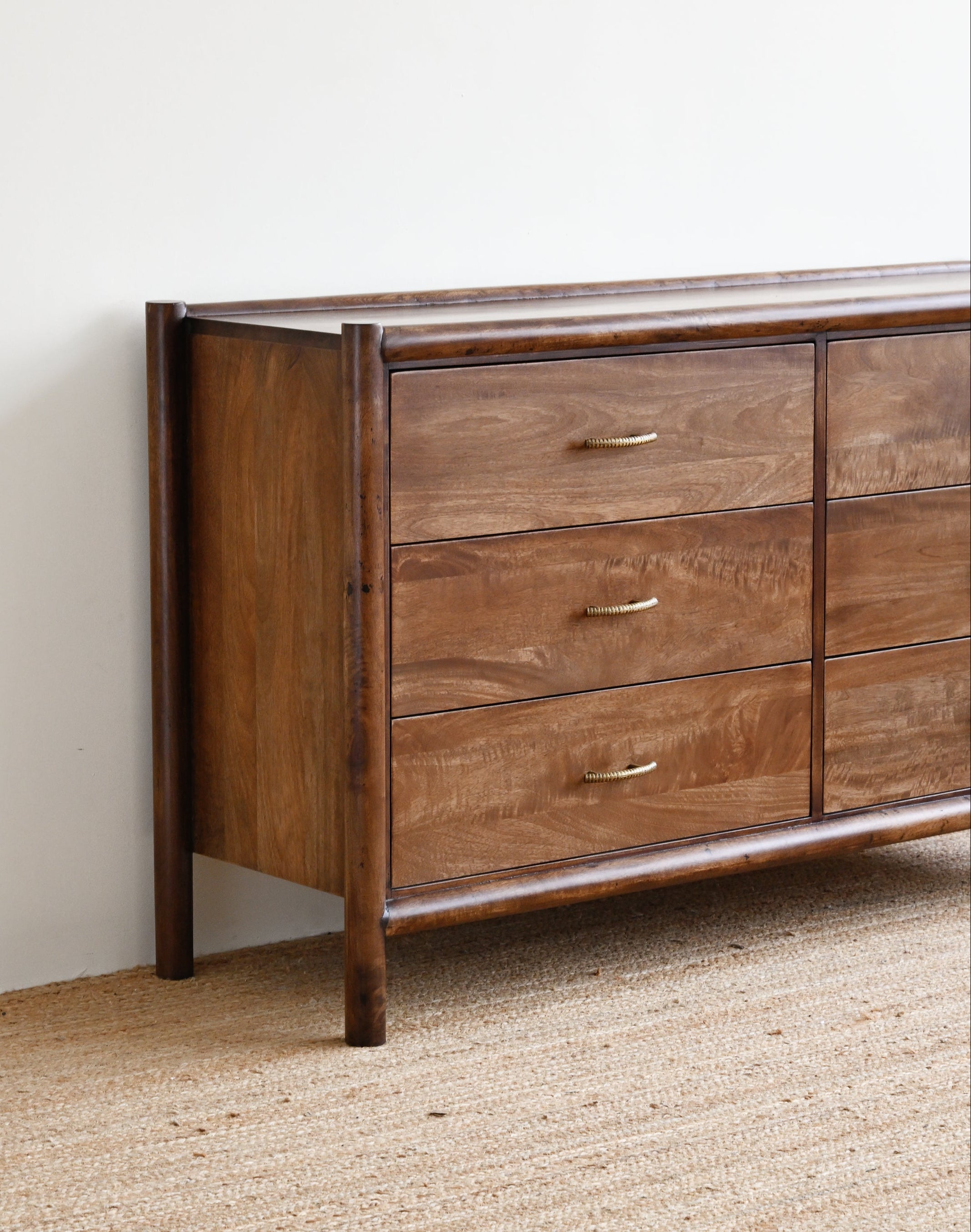 Wooden dresser against a white wall on a beige carpet
