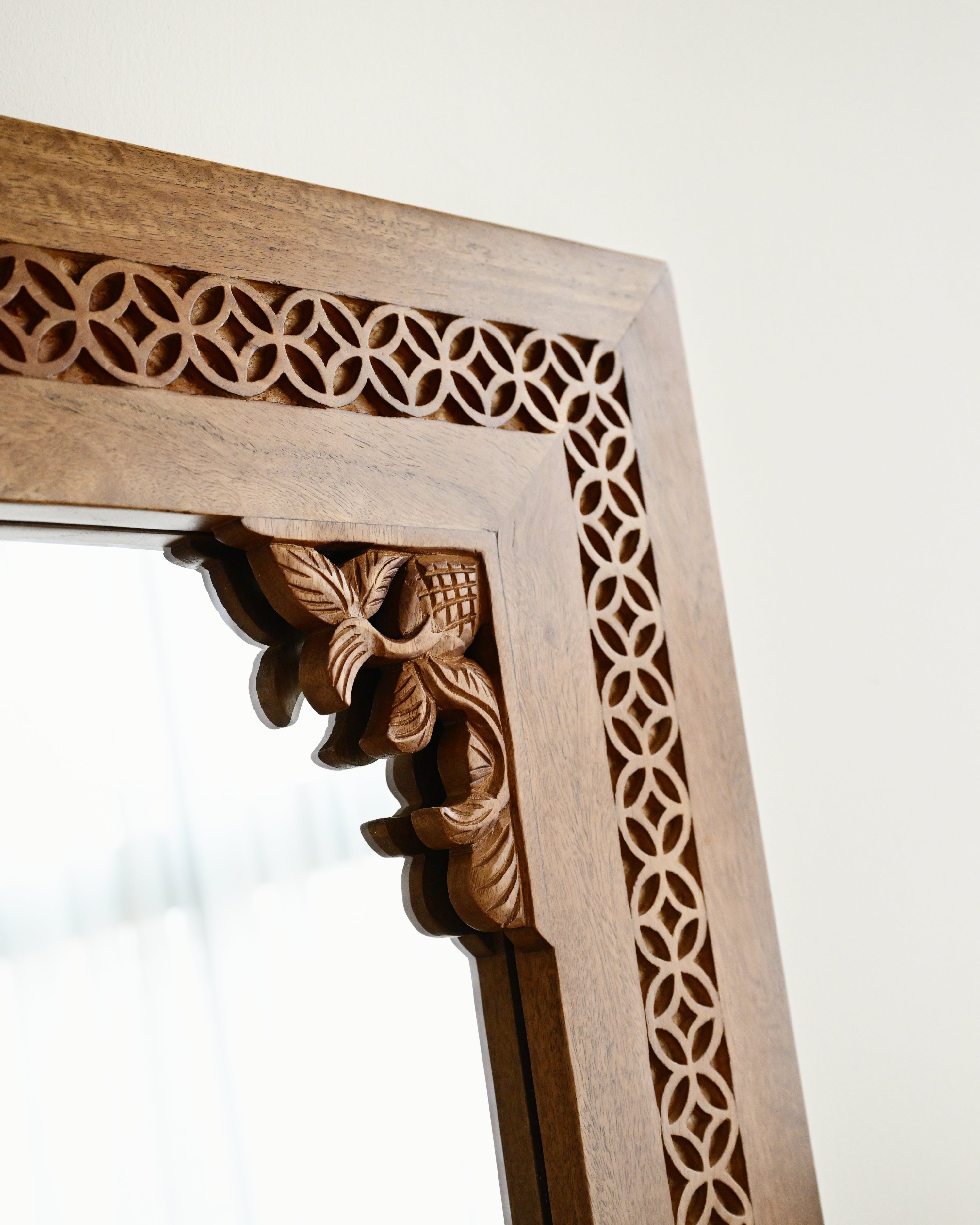 Wooden mirror frame with intricate carvings on a white background