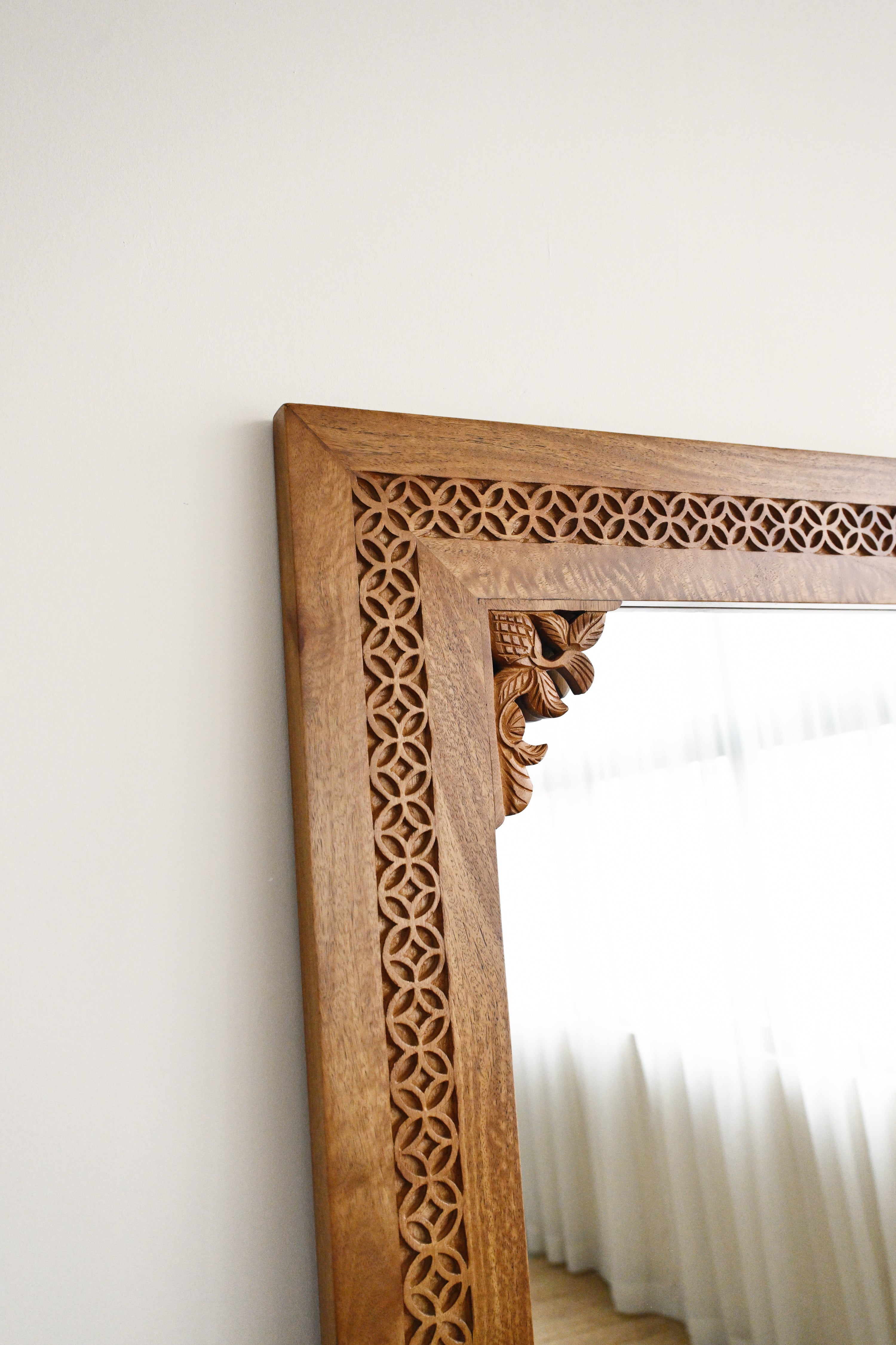 Wooden mirror with intricate carvings on a white wall