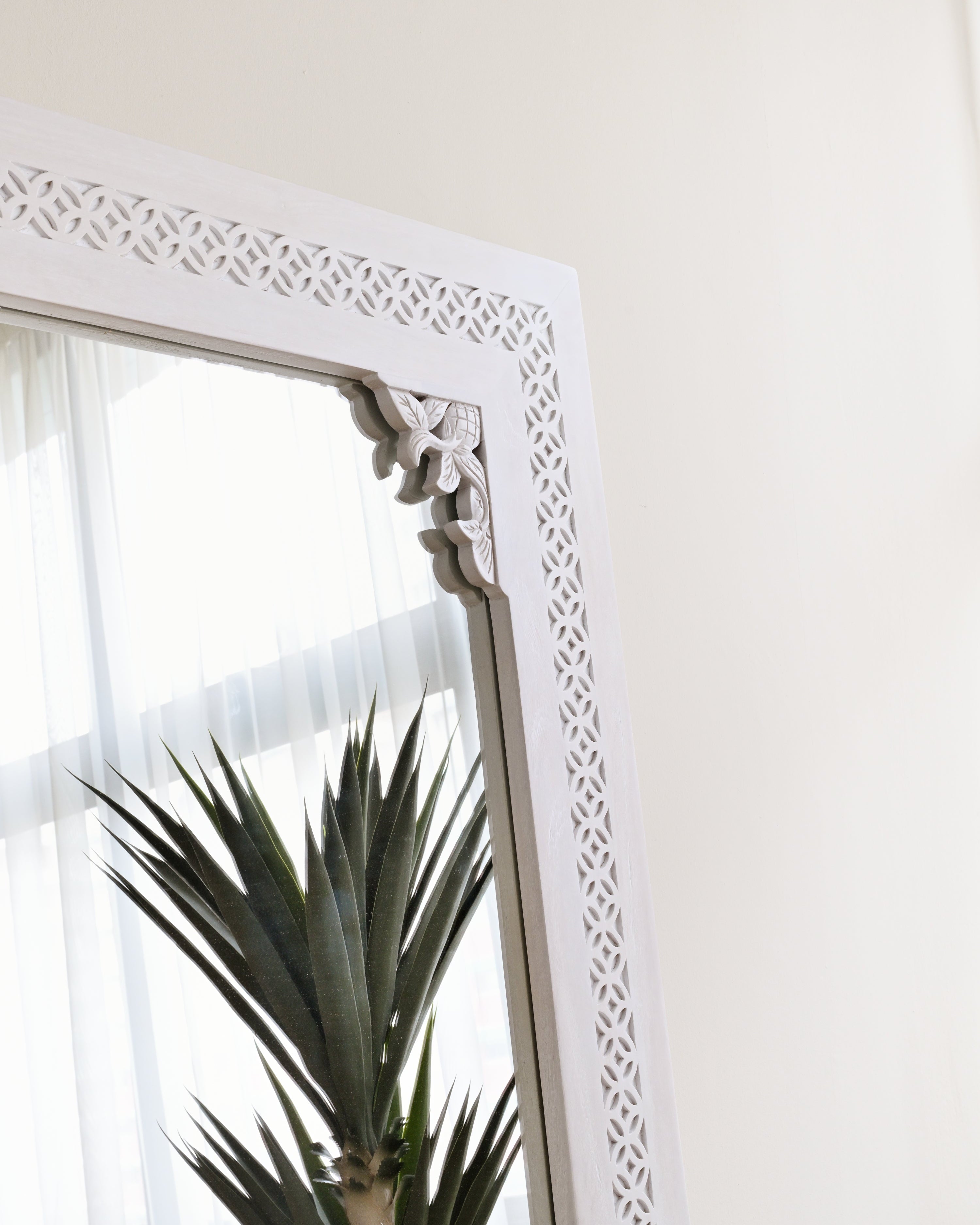 Decorative white mirror with intricate patterns on a light background