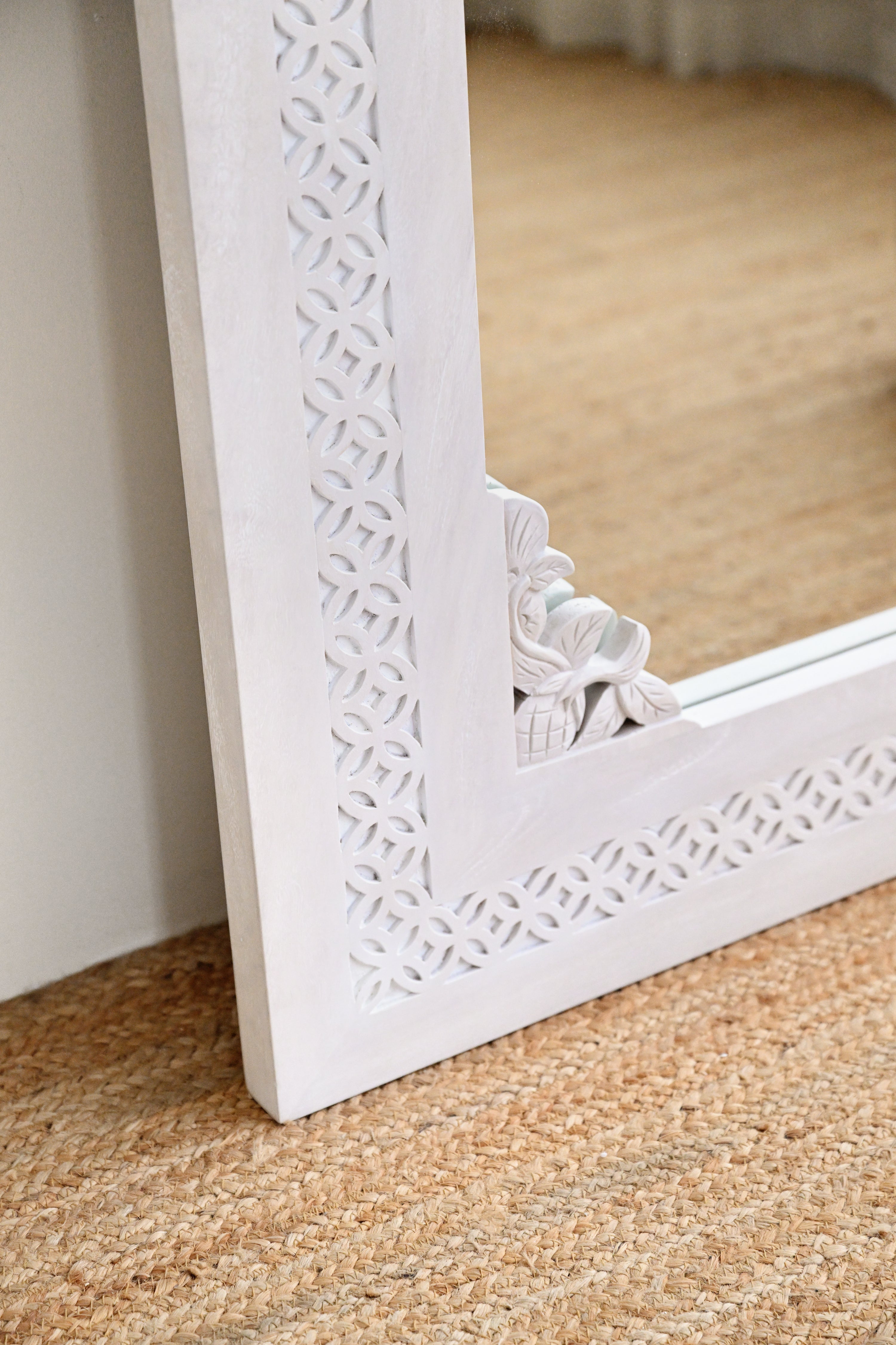 White decorative mirror with intricate patterns on a textured surface
