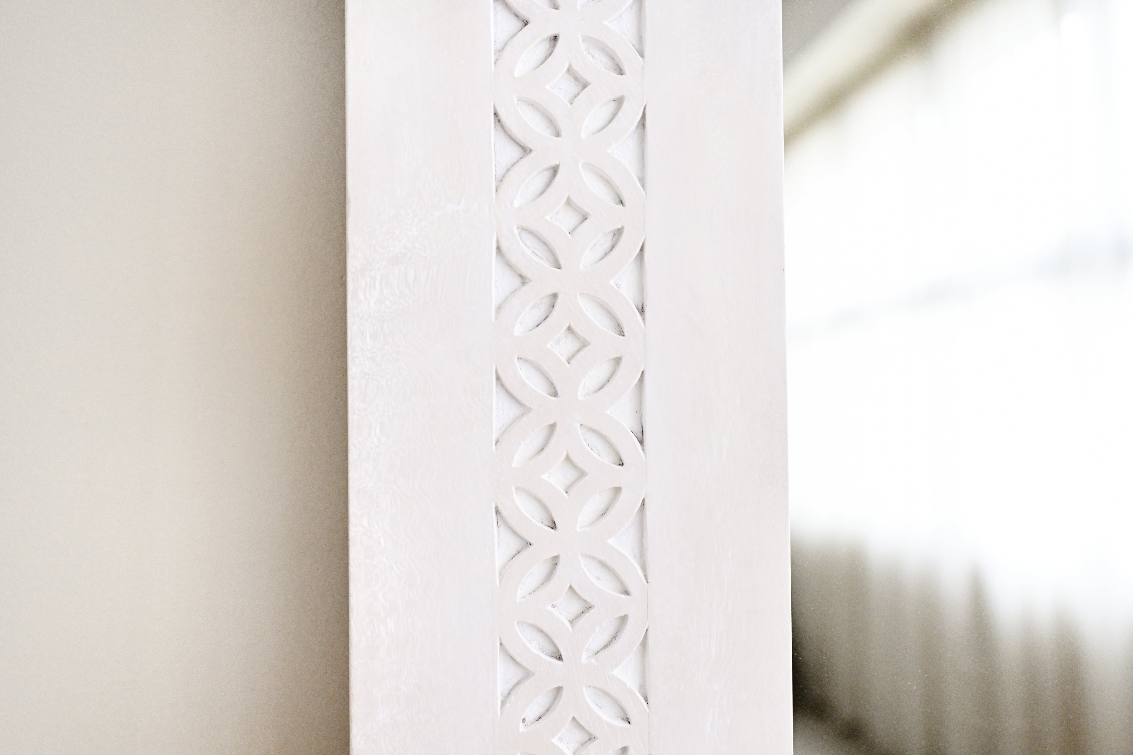 Decorative white radiator with intricate cut-out design on a neutral background