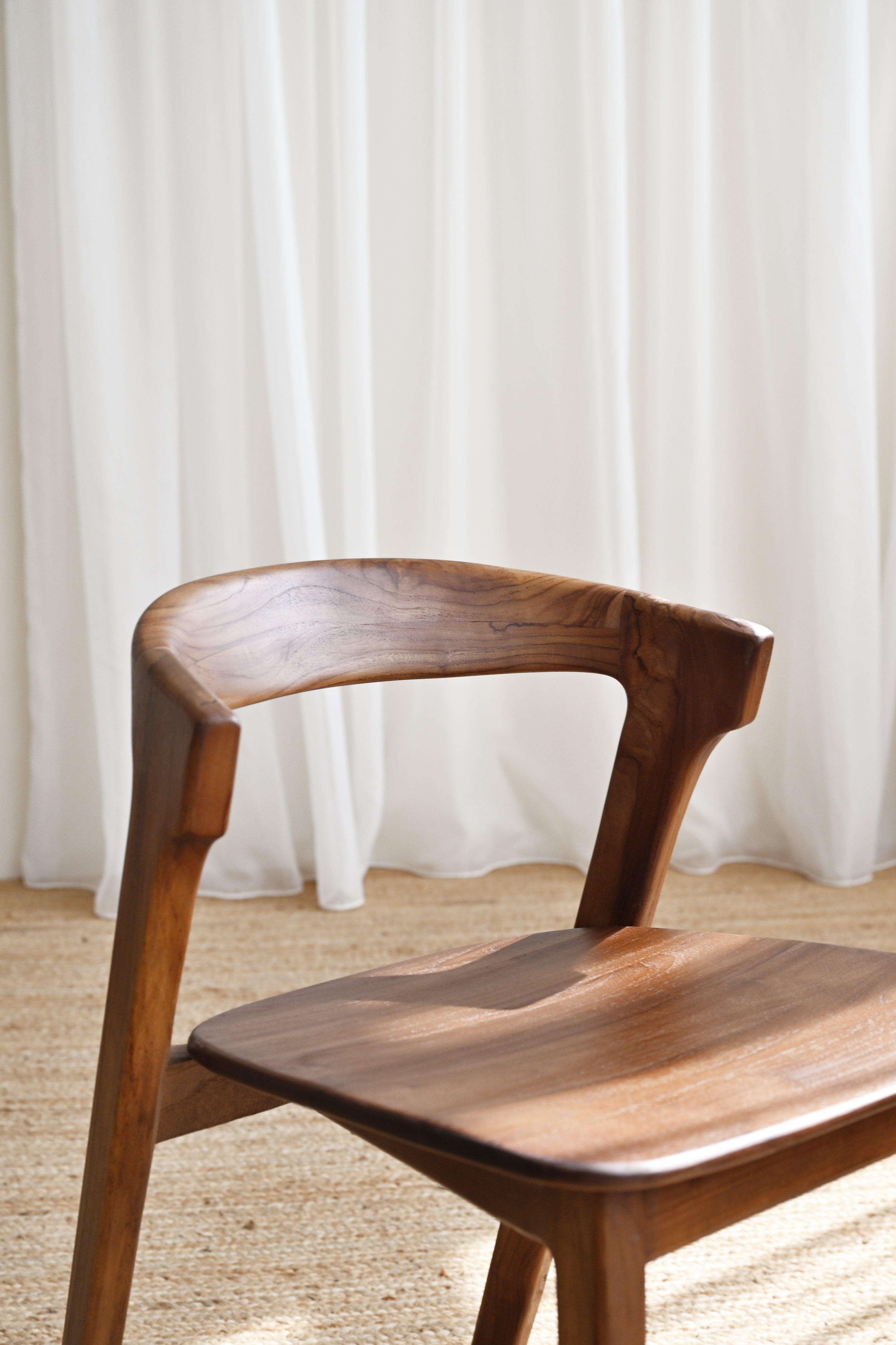 Wooden chair against a white curtain background