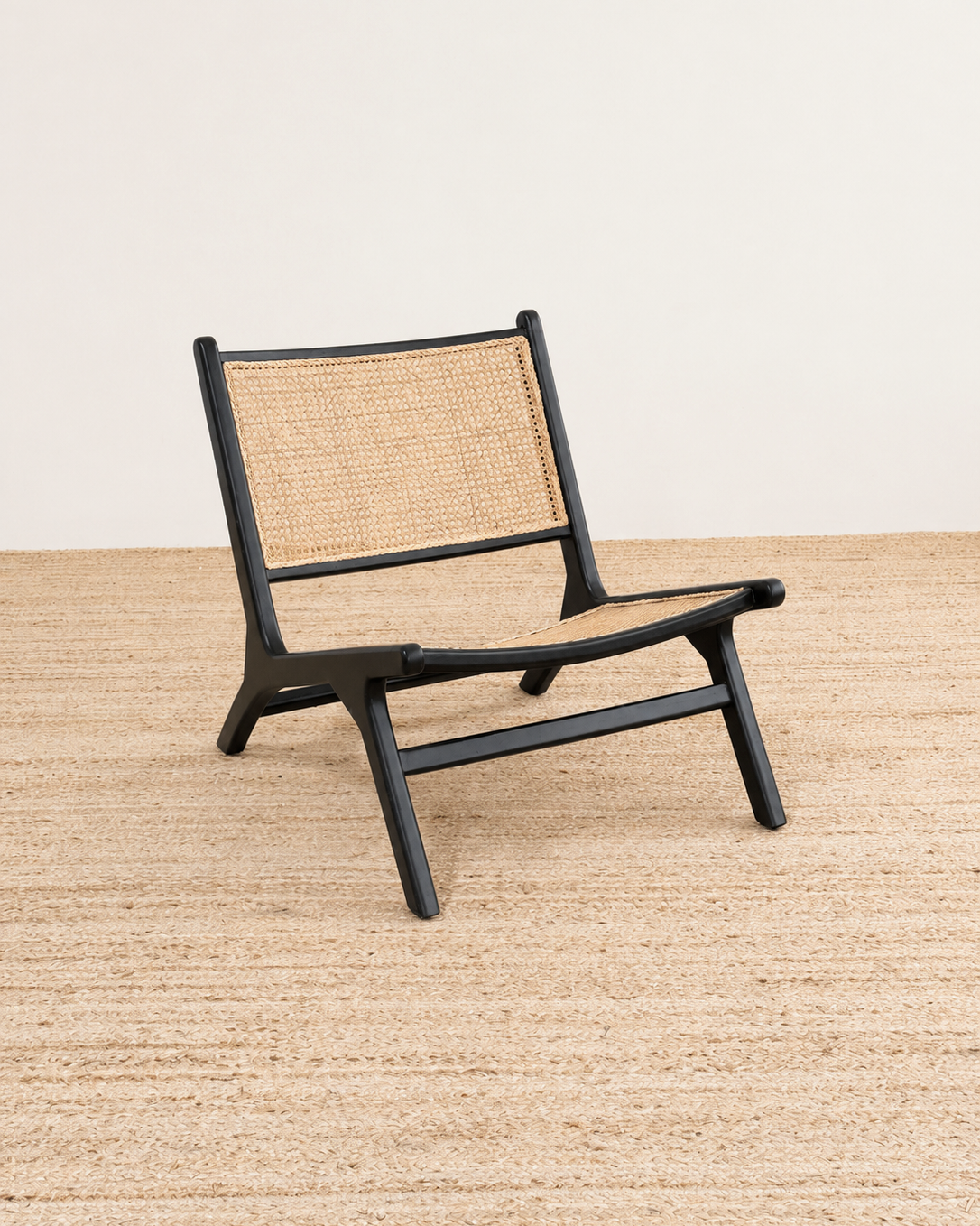 Black chair with woven backrest on a beige surface