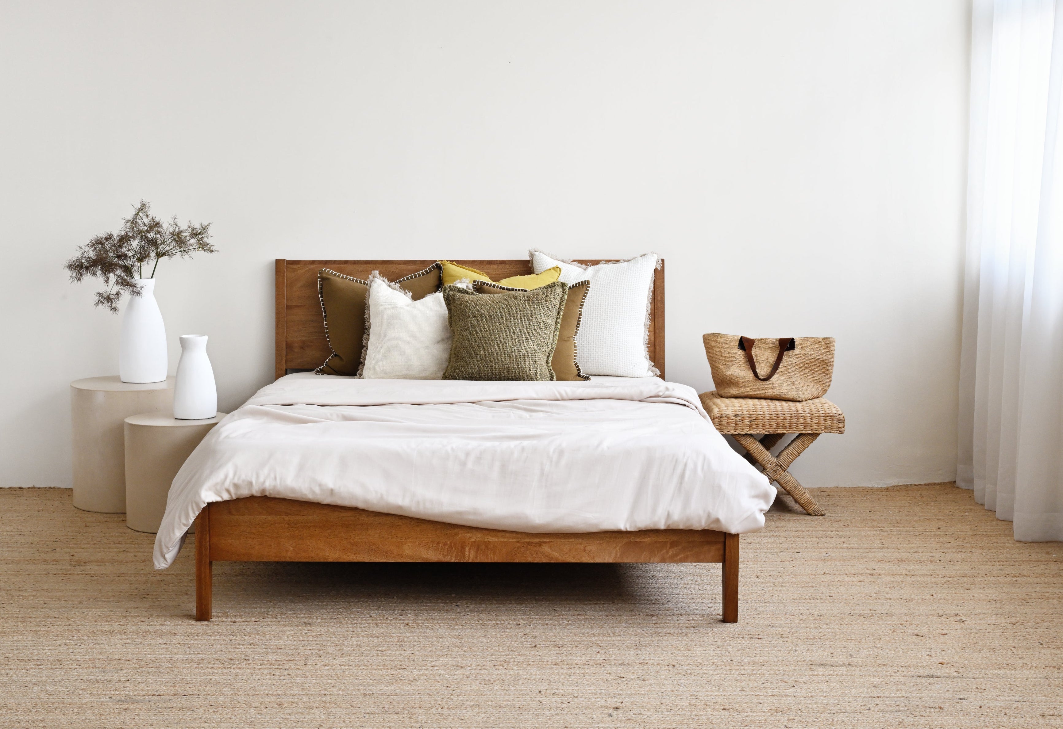 Wooden bed with white bedding and pillows in a minimalistic bedroom.