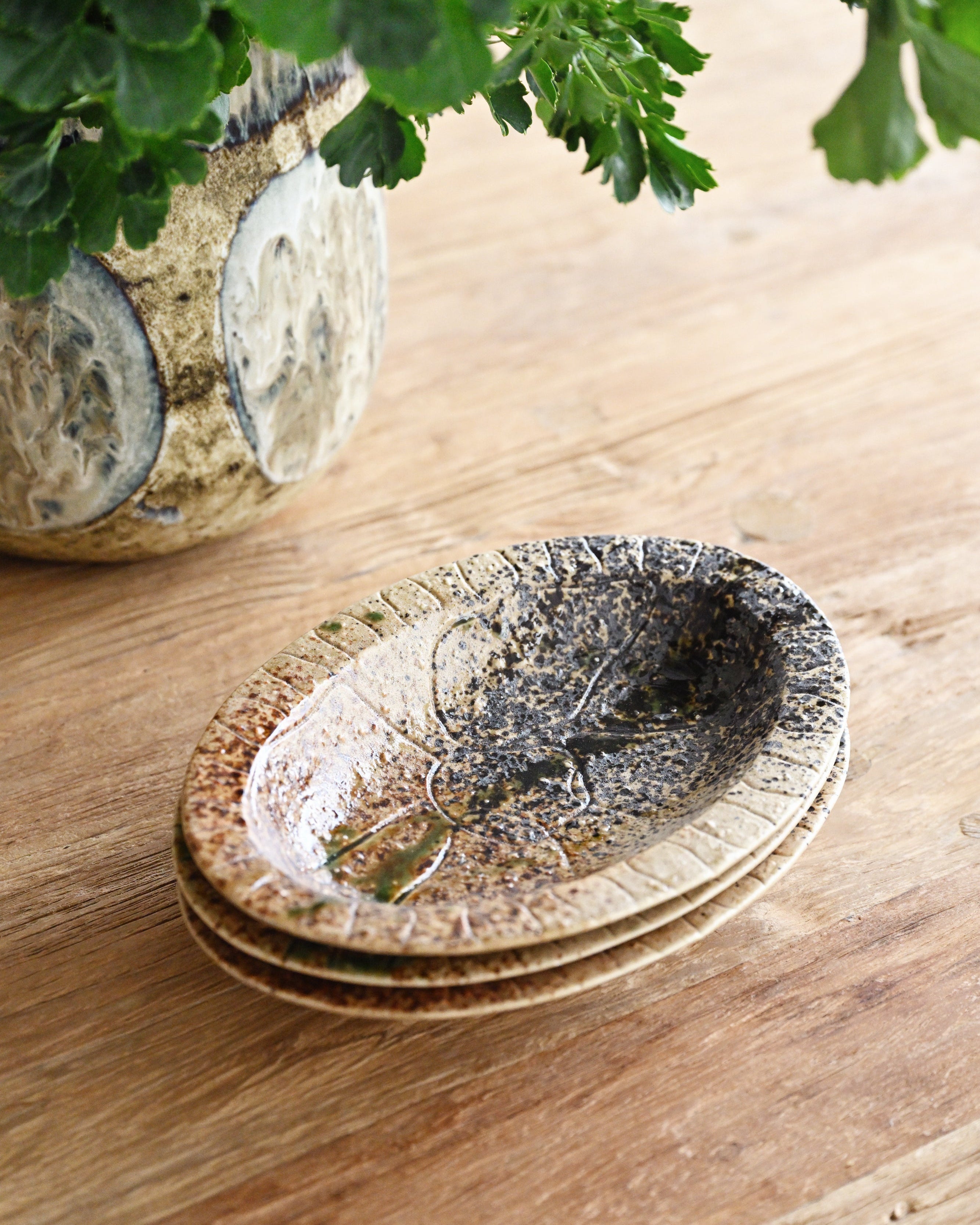Stack of ceramic bowls on a wooden surface with greenery in the background