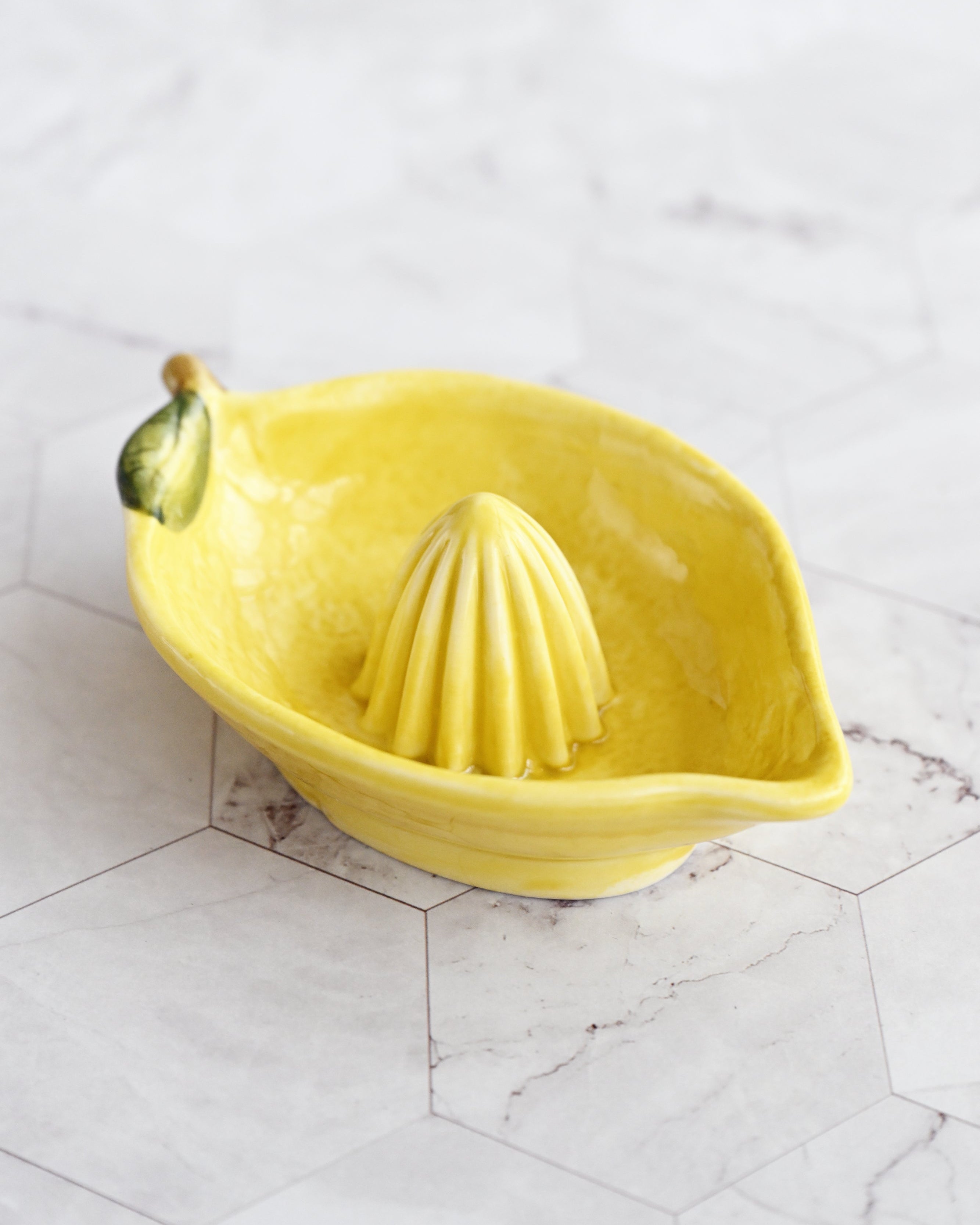 Yellow lemon-shaped citrus juicer on a marble surface
