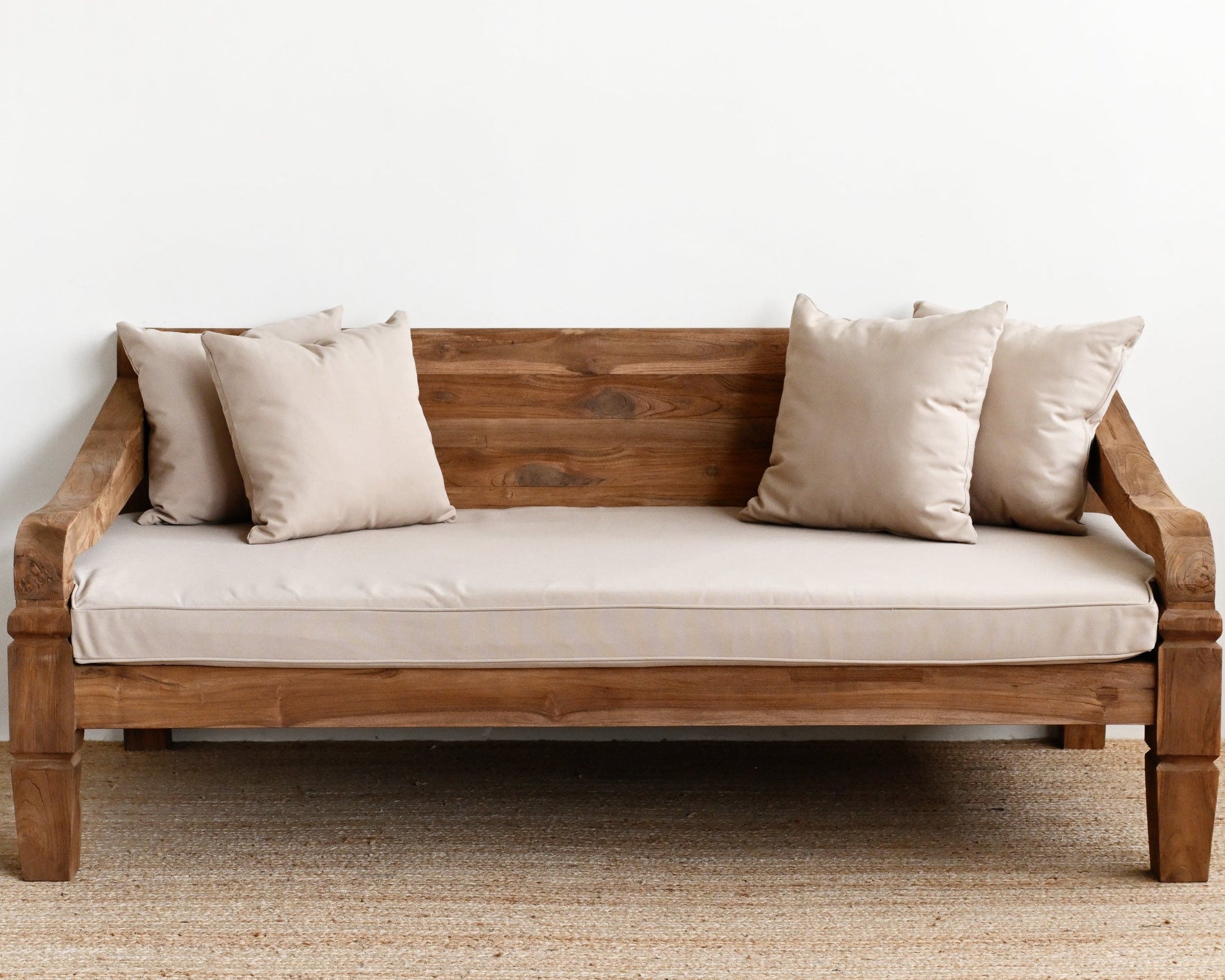 Wooden sofa with beige cushions on a plain white wall background