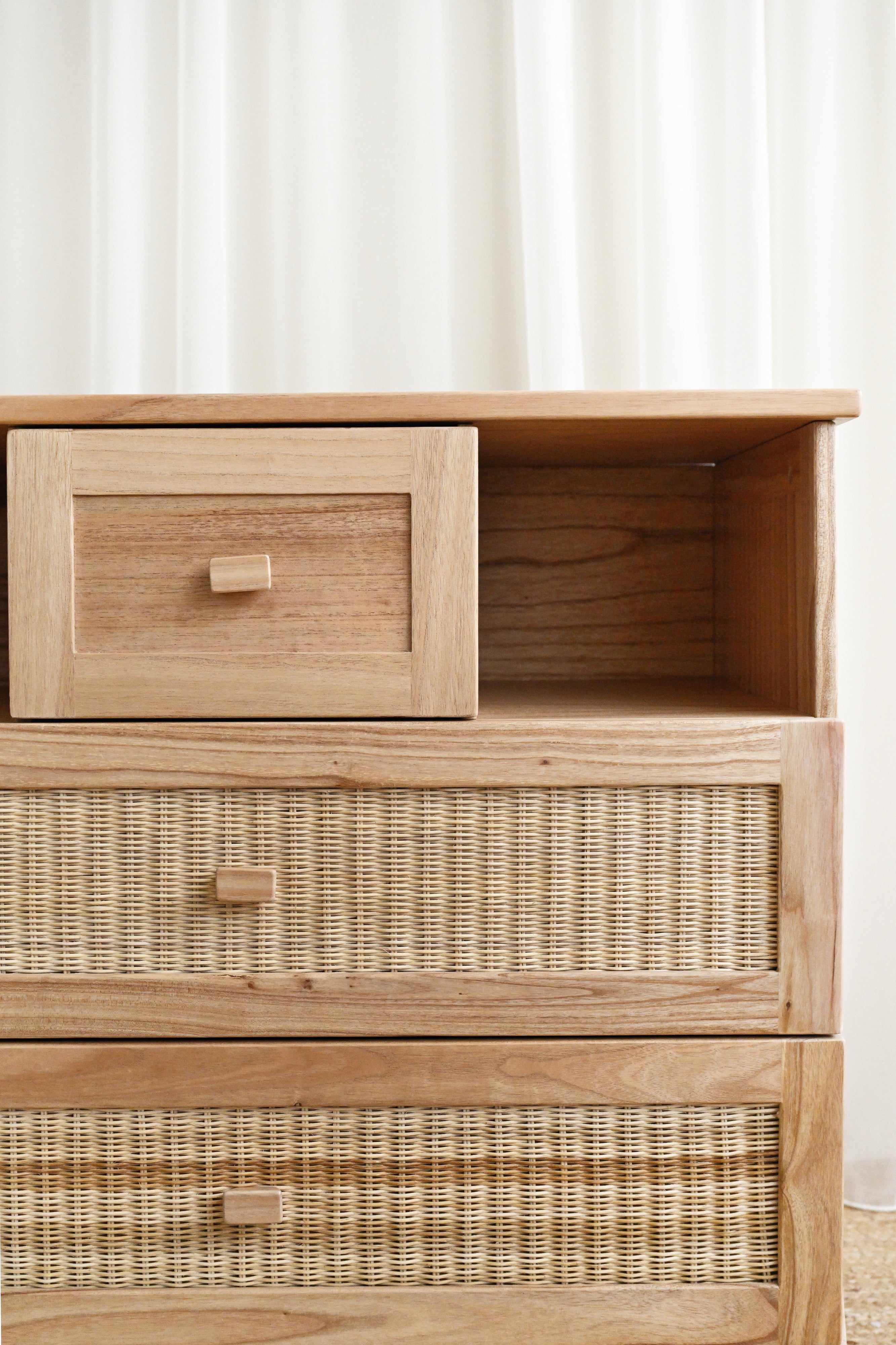 Wooden dresser with wicker drawers against a white wall