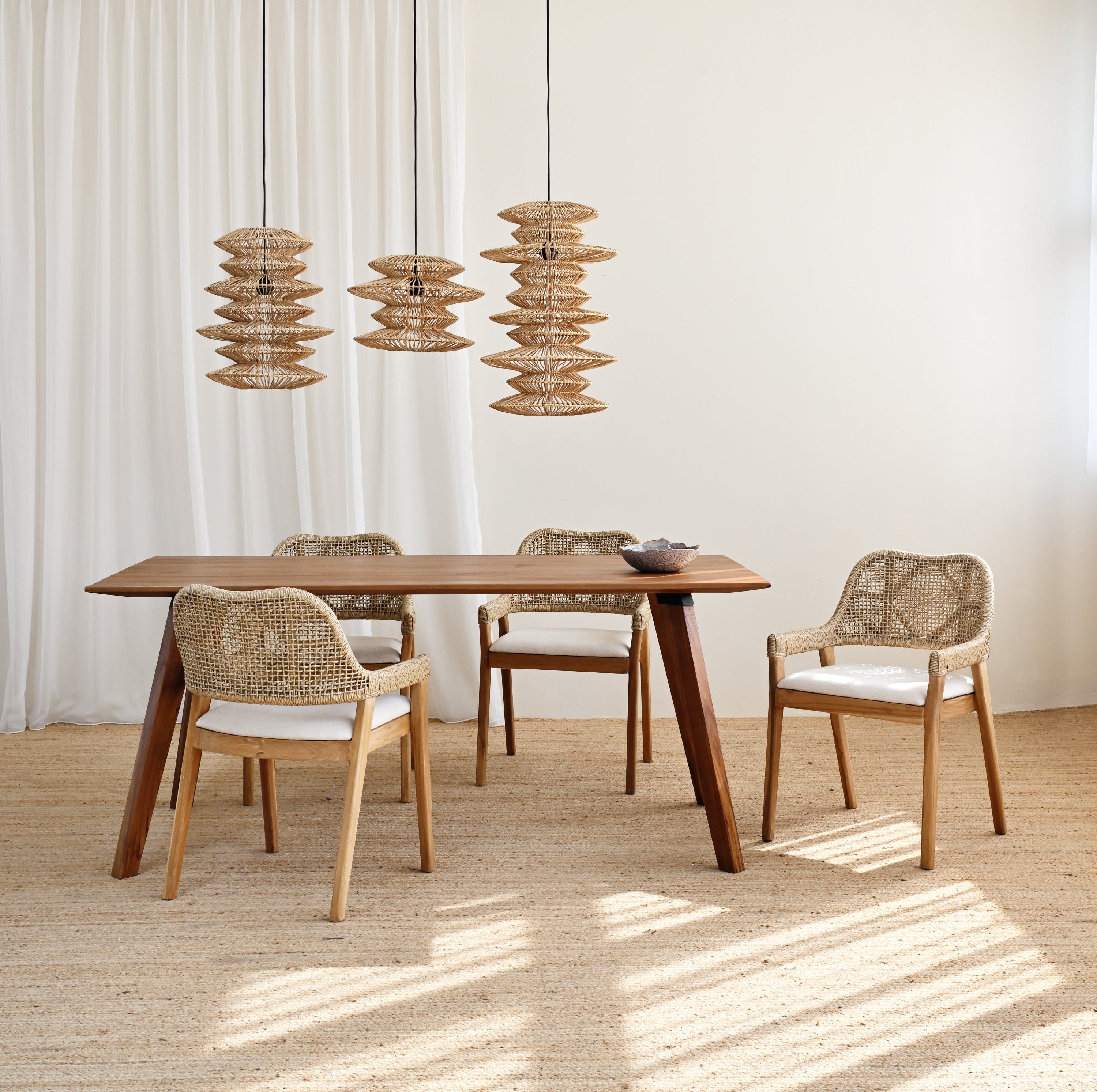Dining area with wooden table and chairs under pendant lights in a bright room.