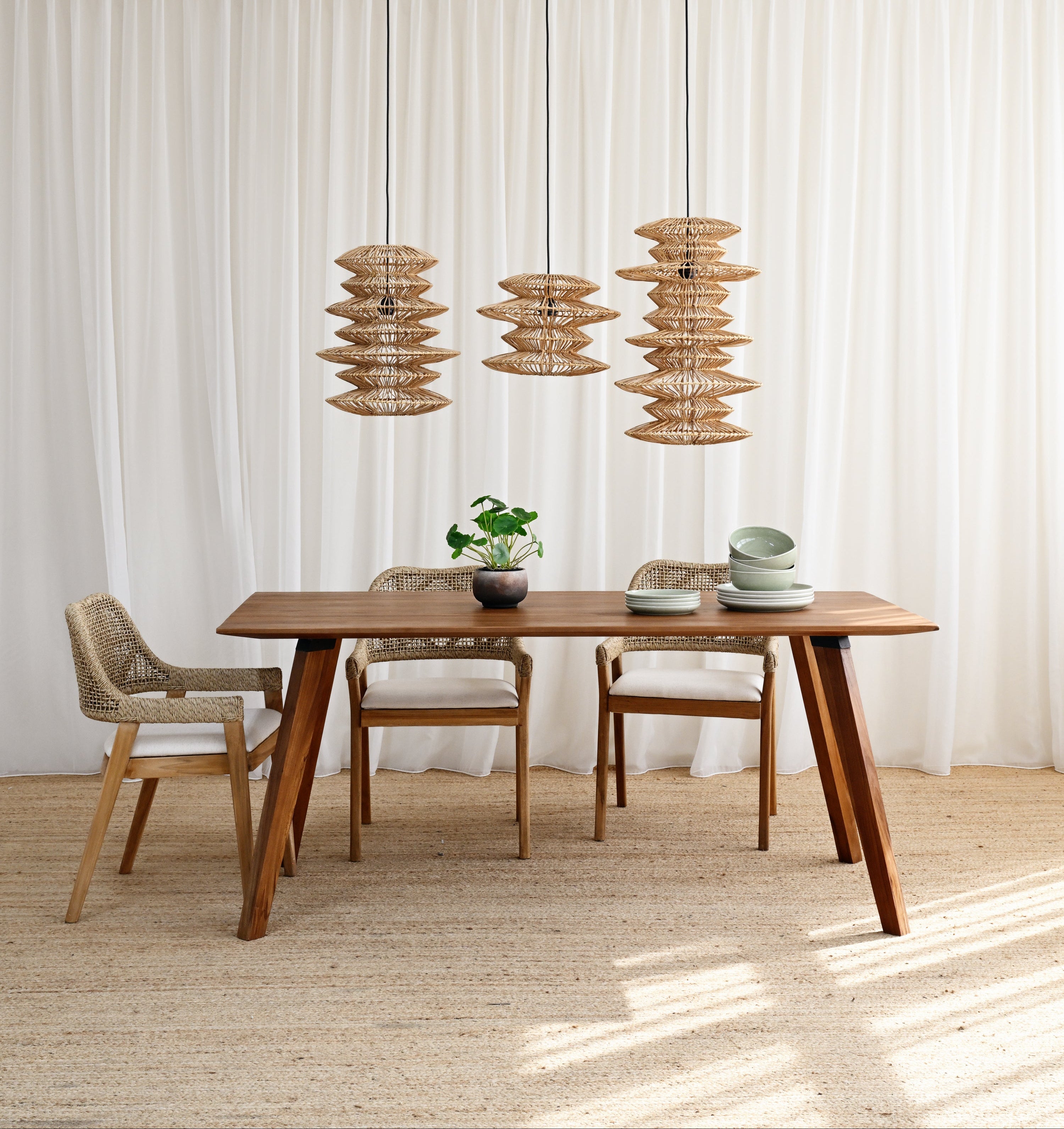 Dining area with wooden table and chairs under pendant lights in a bright room.