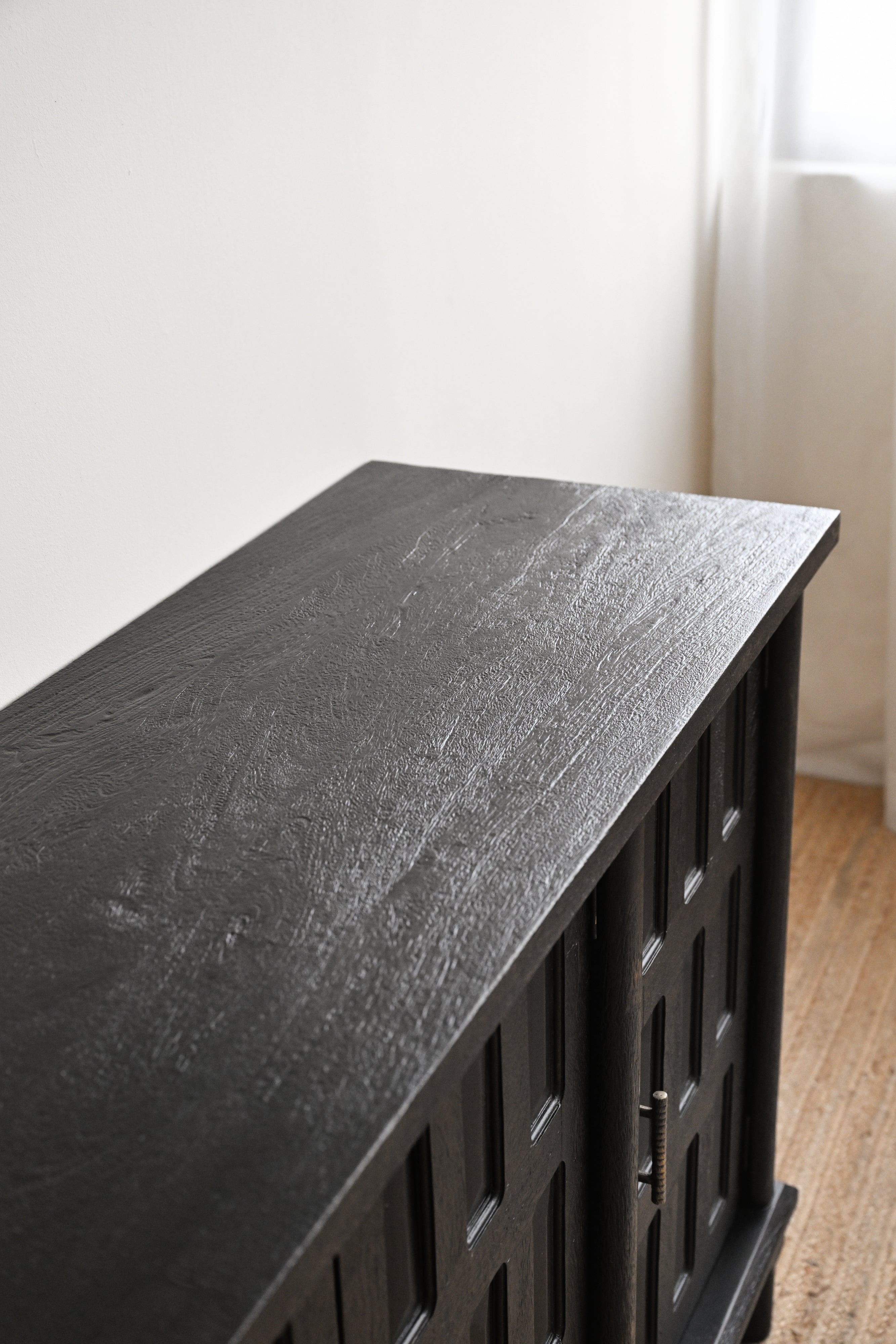 Black metal cabinet with a textured surface on a wooden floor.