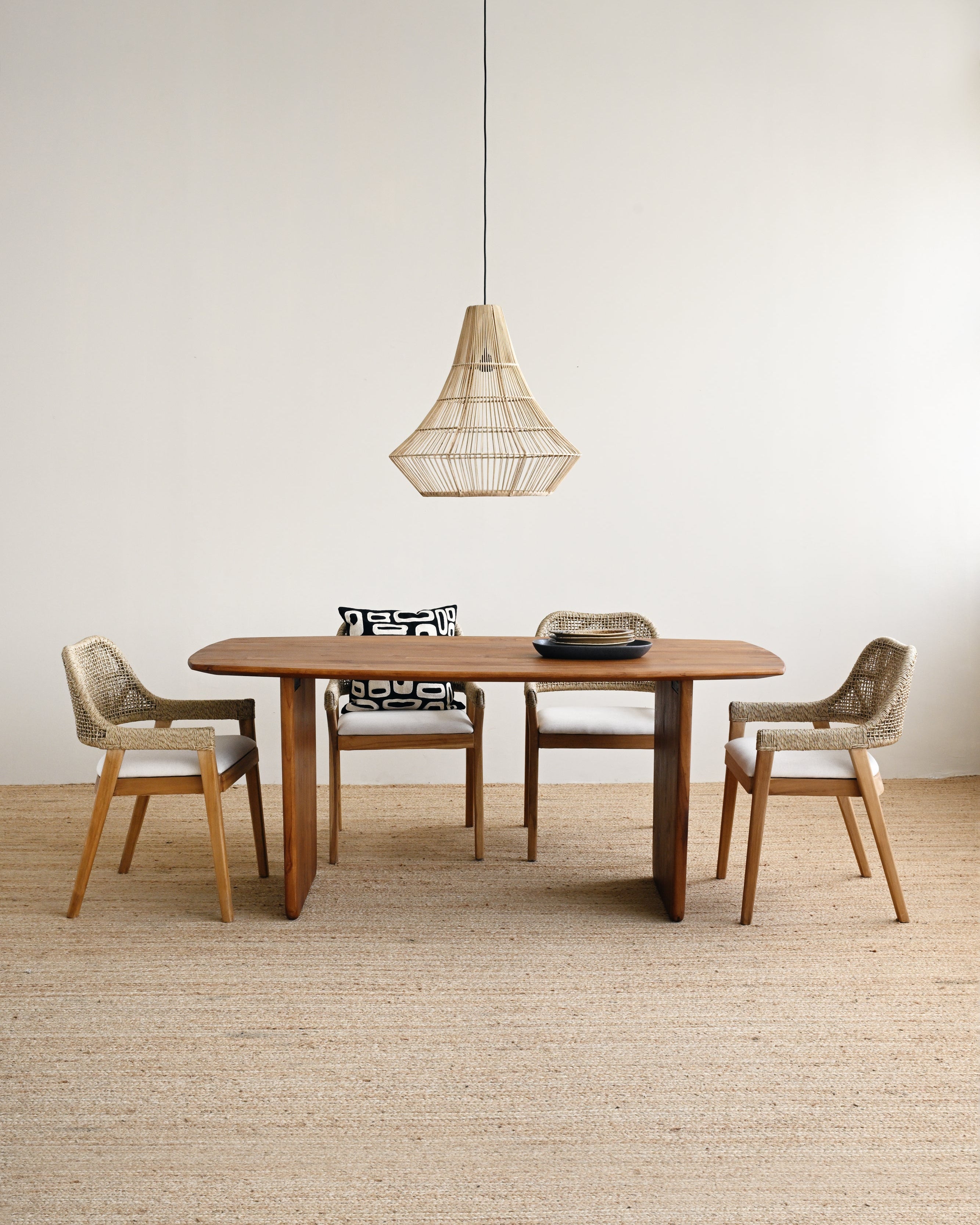 Dining area with wooden table and chairs under a pendant light in a minimalistic room.
