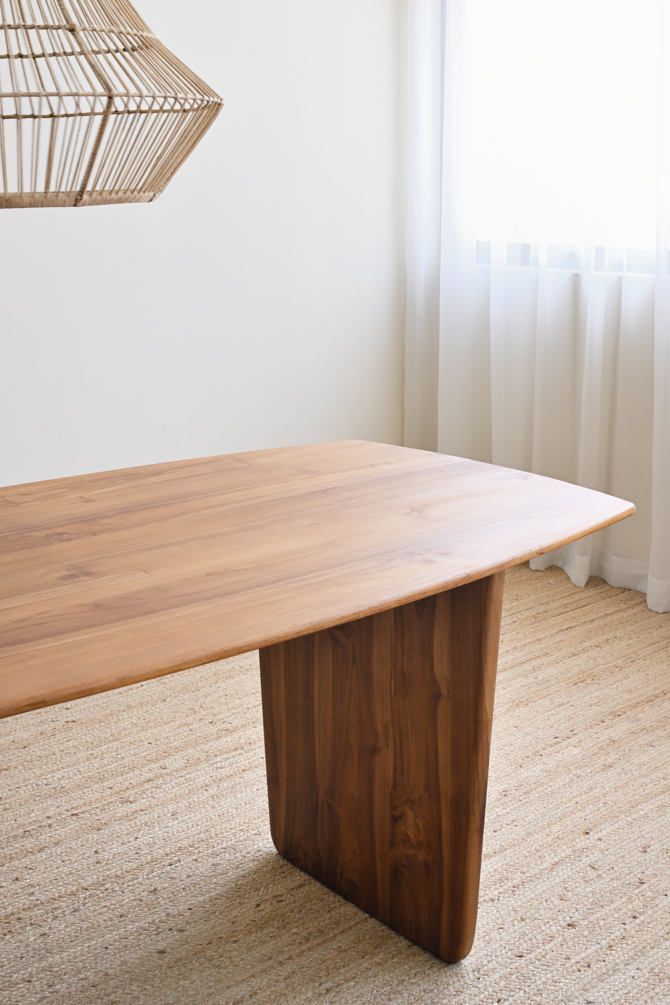 Wooden dining table in a room with a lamp and curtains.