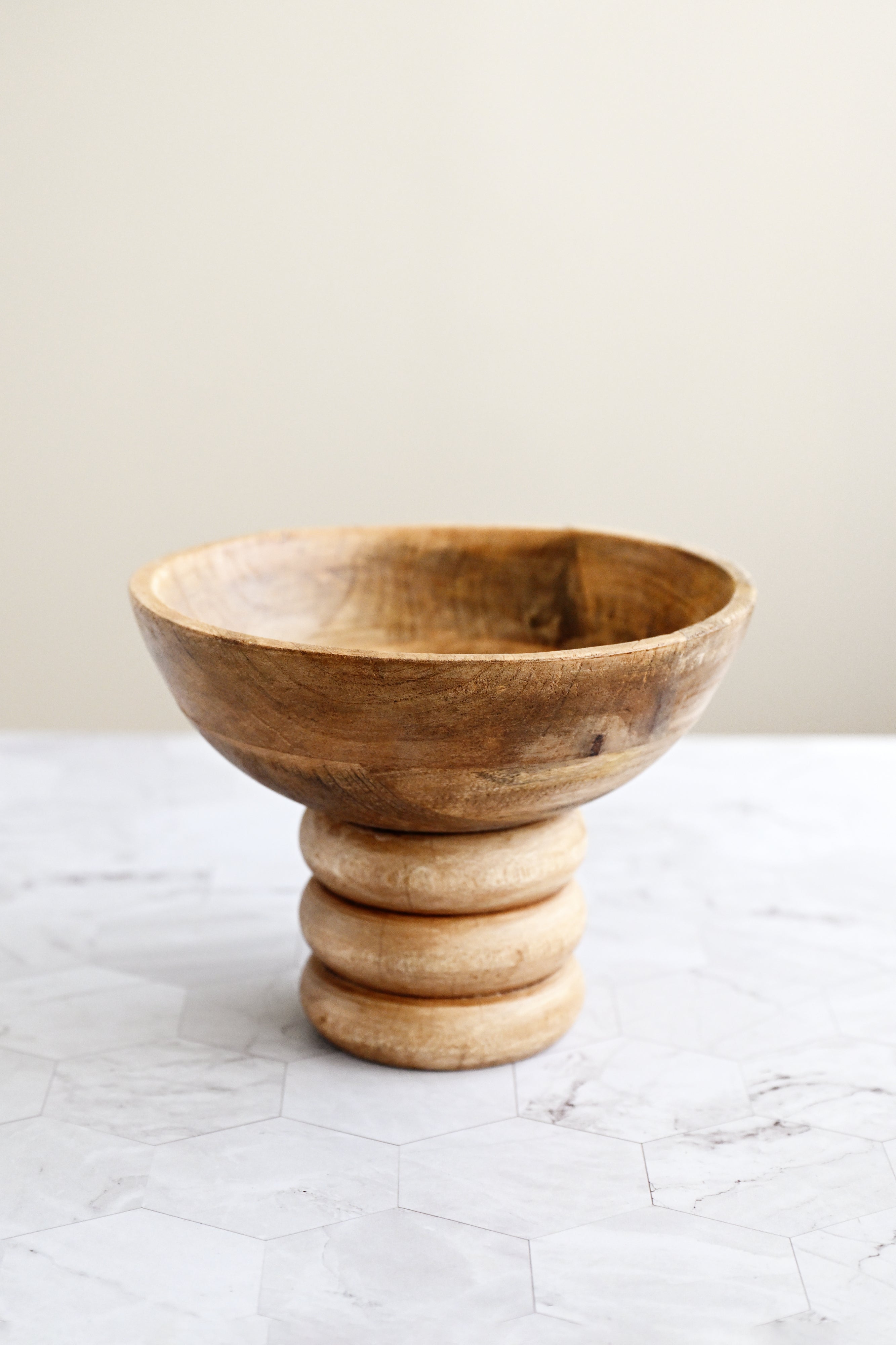 Wooden bowl with a stacked design on a marble surface