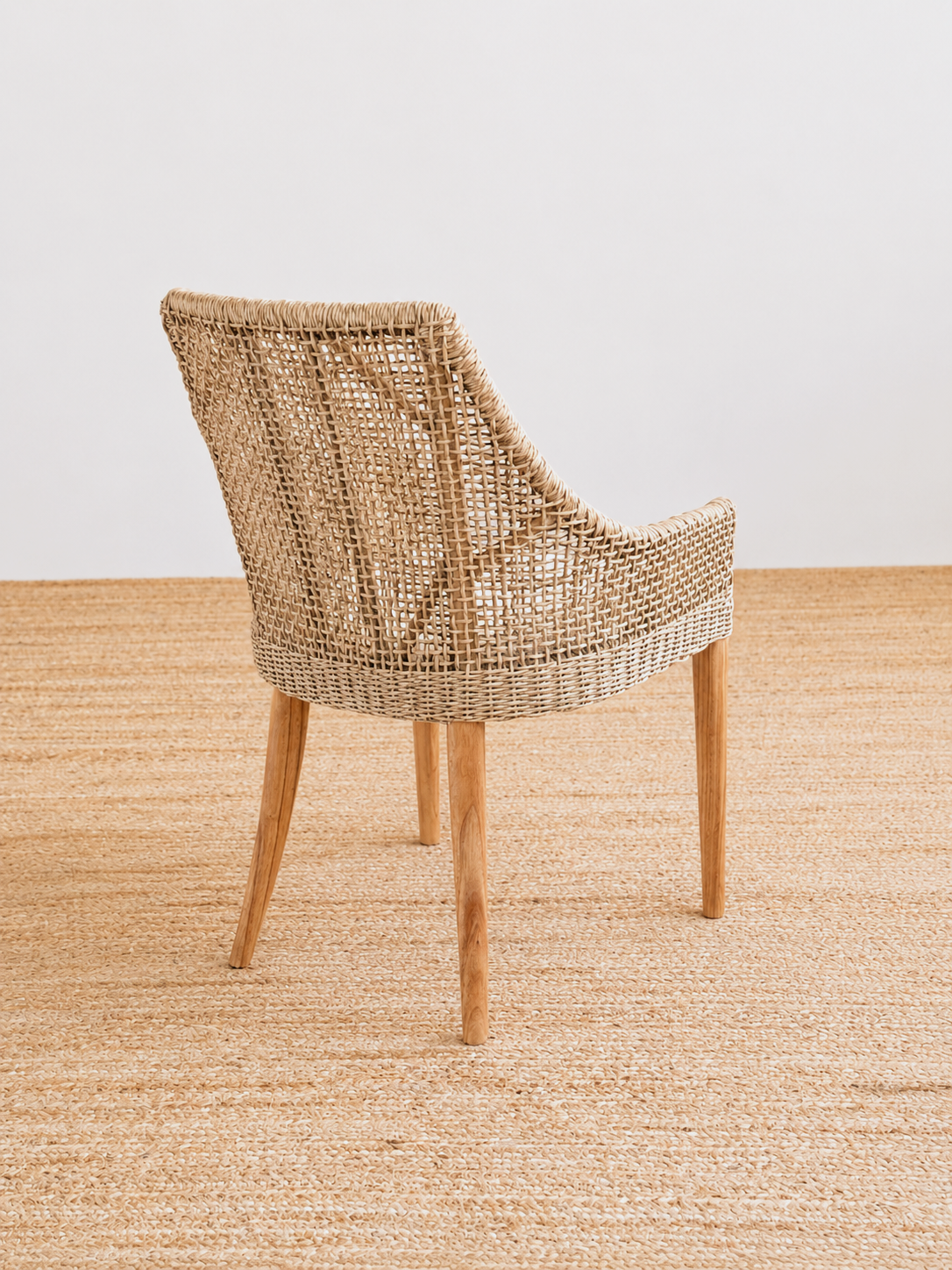 Woven chair on a textured beige surface with a neutral background