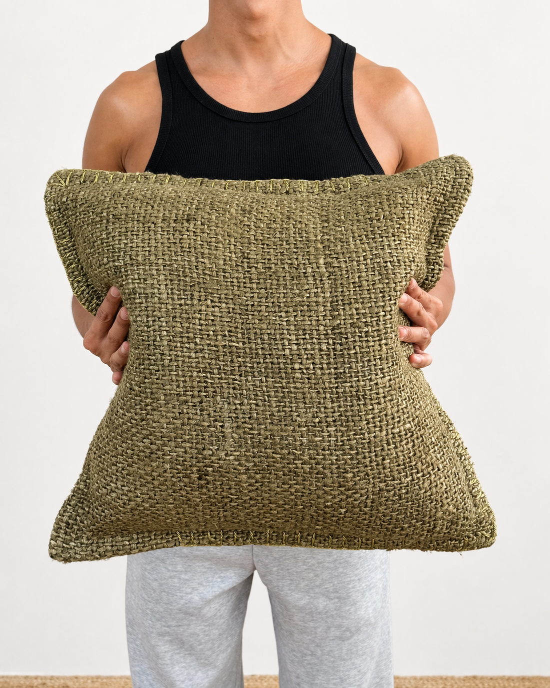 Person holding a textured green pillow against a white background