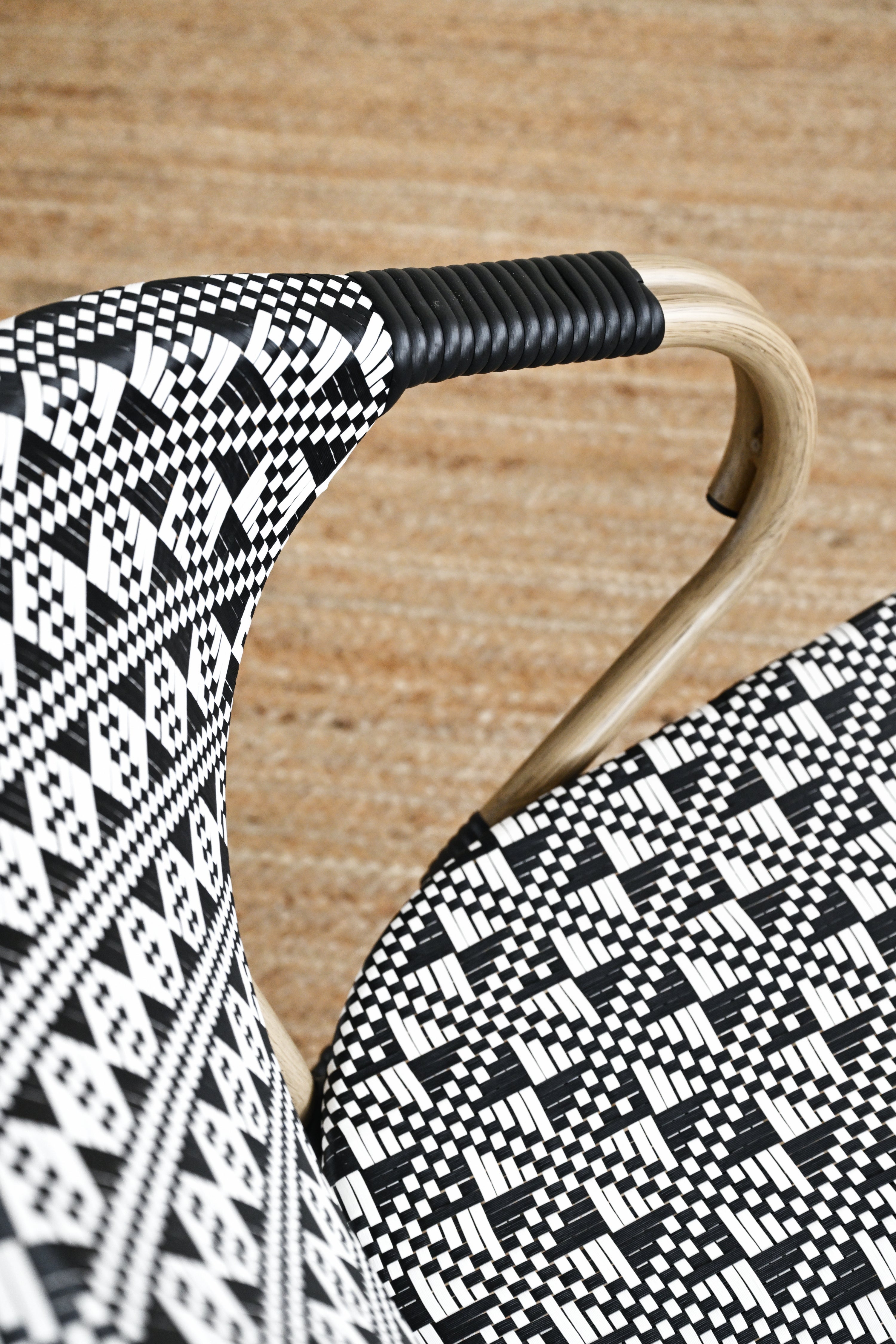 Close-up of a chair with black and white patterned seat and backrest on a wooden floor.