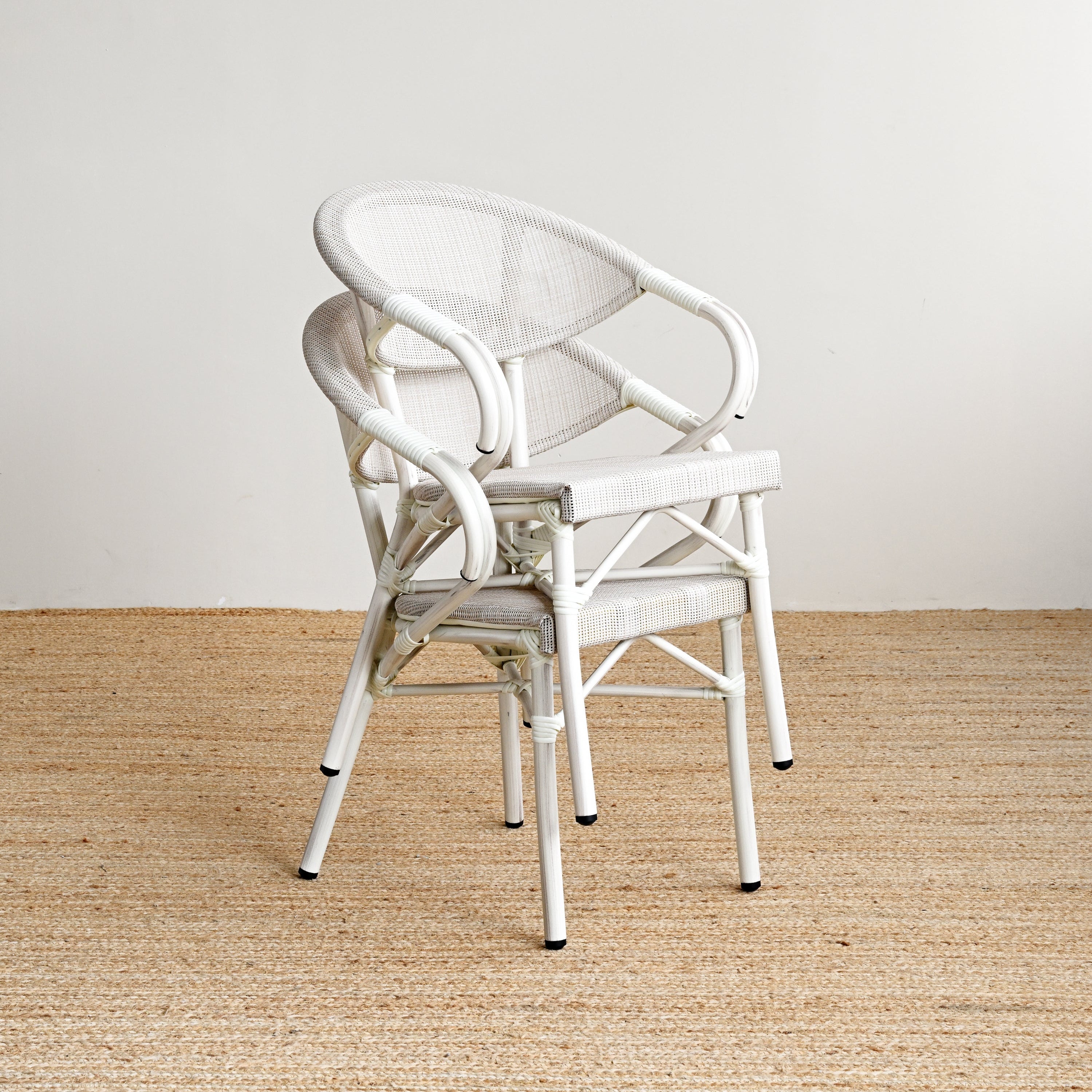 White chair on a beige woven rug with a plain white wall background