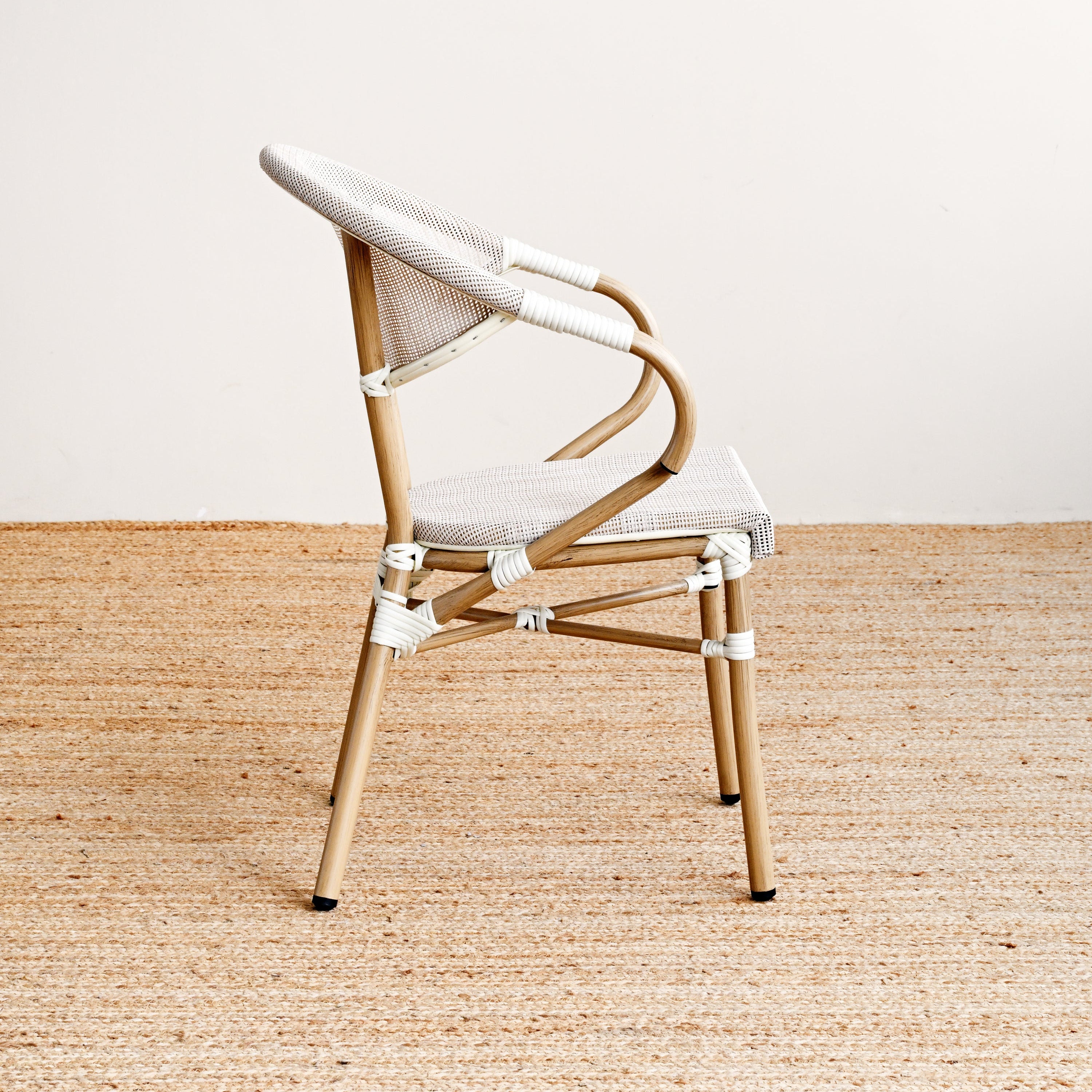 Modern chair with wooden frame and white cushion on a beige rug