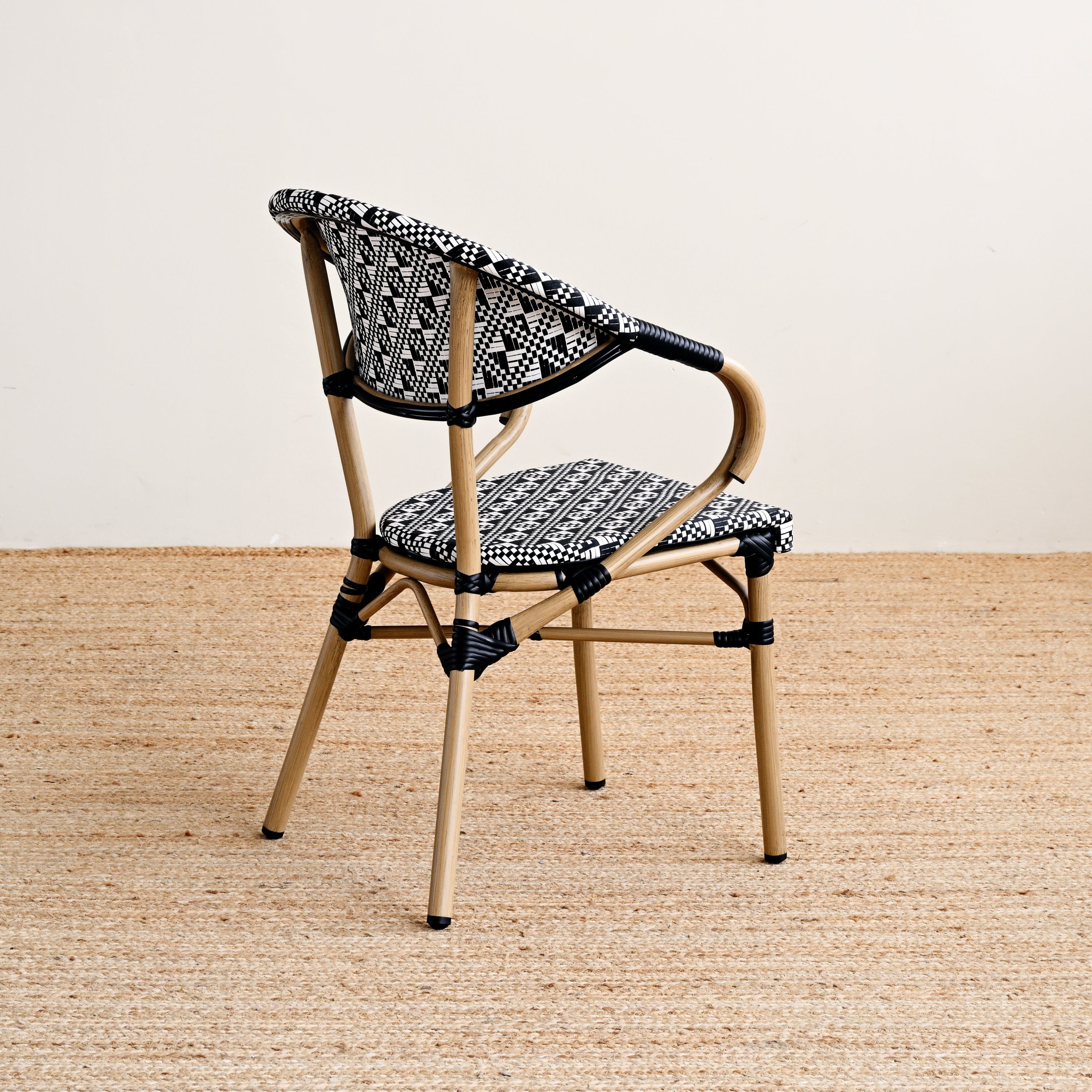 Chair with woven backrest and patterned cushion on a beige floor.