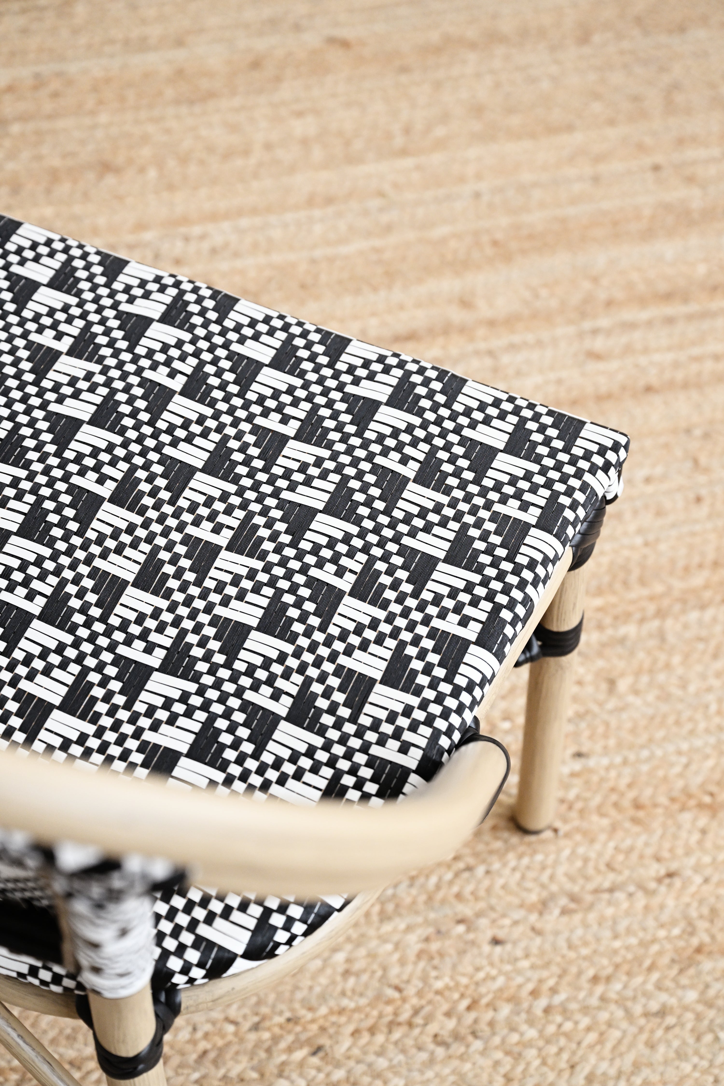 Black and white patterned bench cover on a wooden bench with a beige carpet background