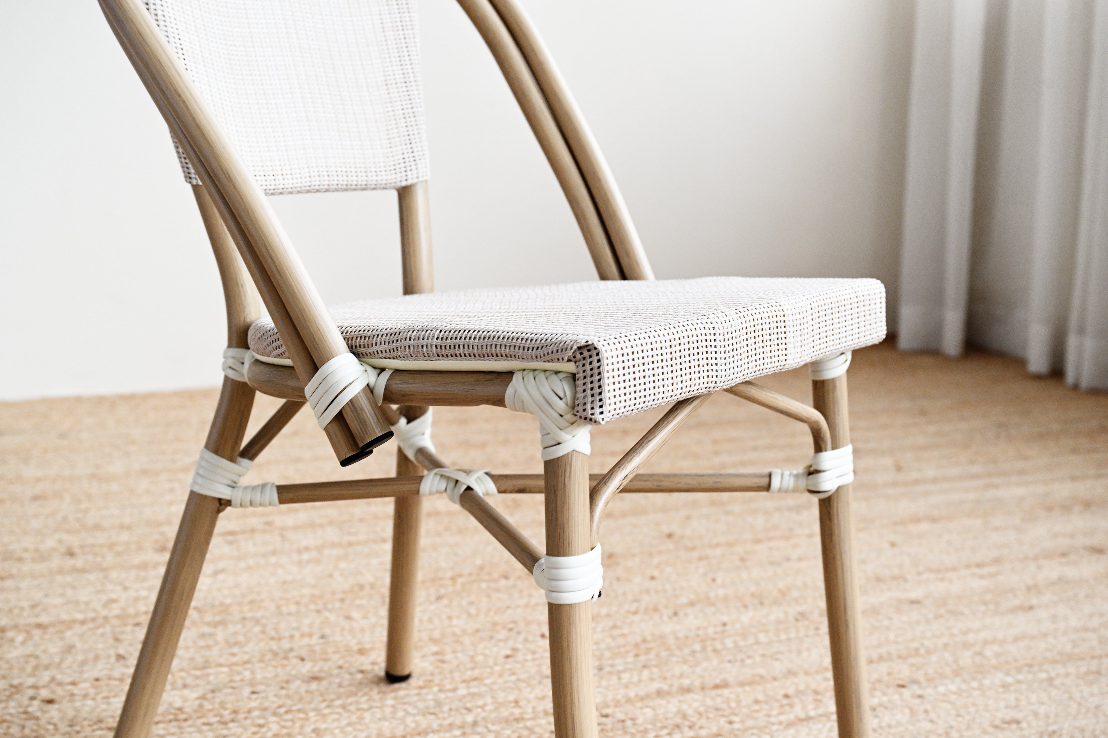 Close-up of a wooden chair with a woven seat on a wooden floor.