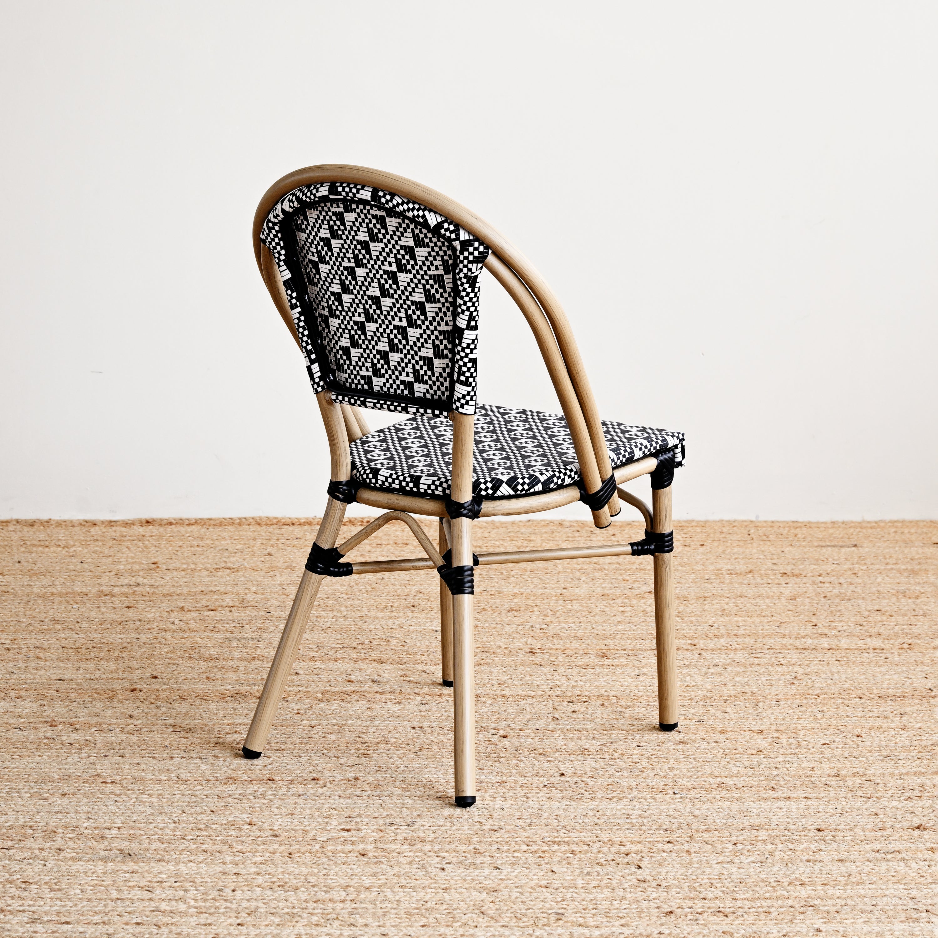 Chair with woven backrest and patterned cushion on a beige floor.