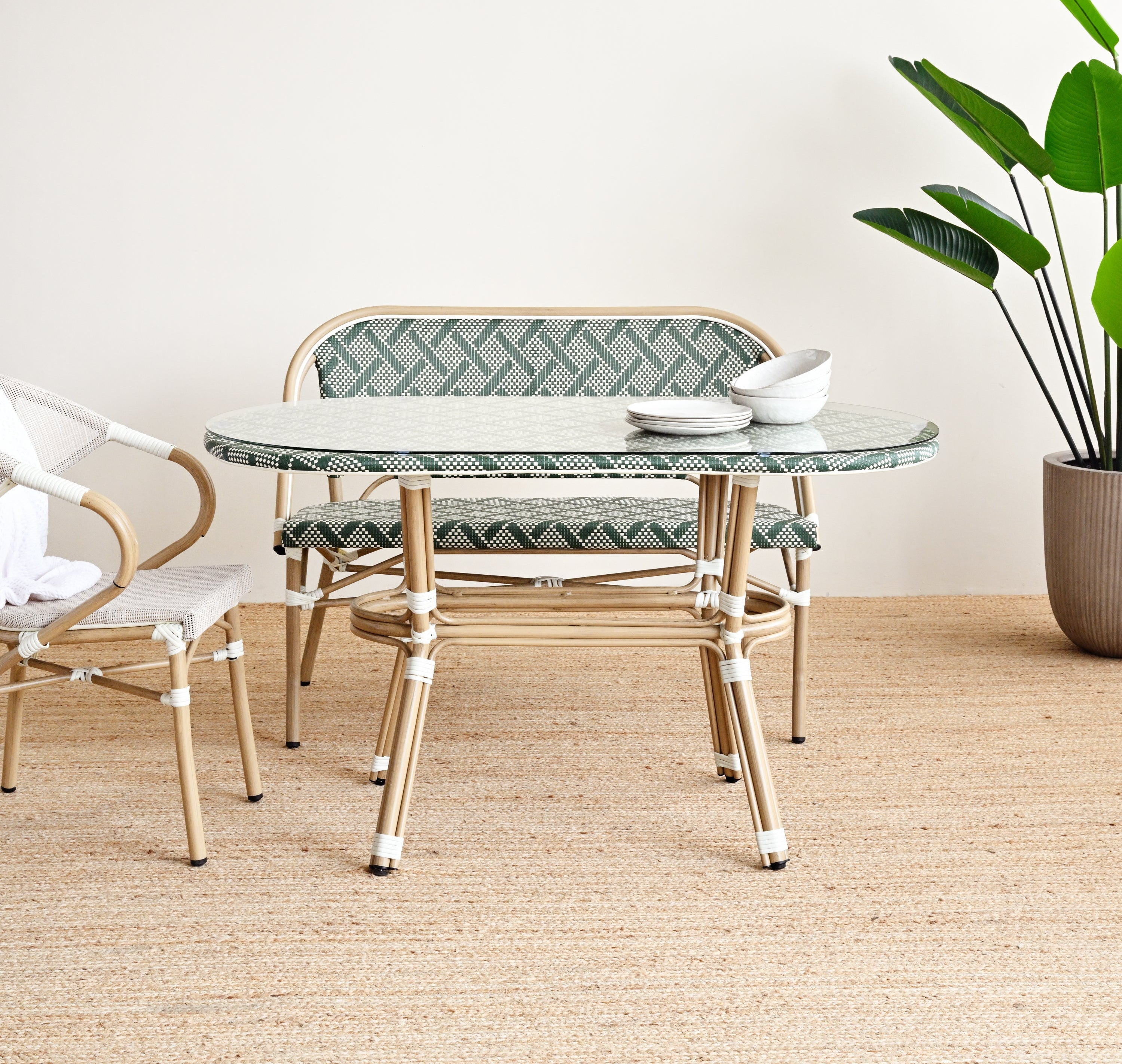Outdoor furniture set with a glass table and chairs on a beige rug.