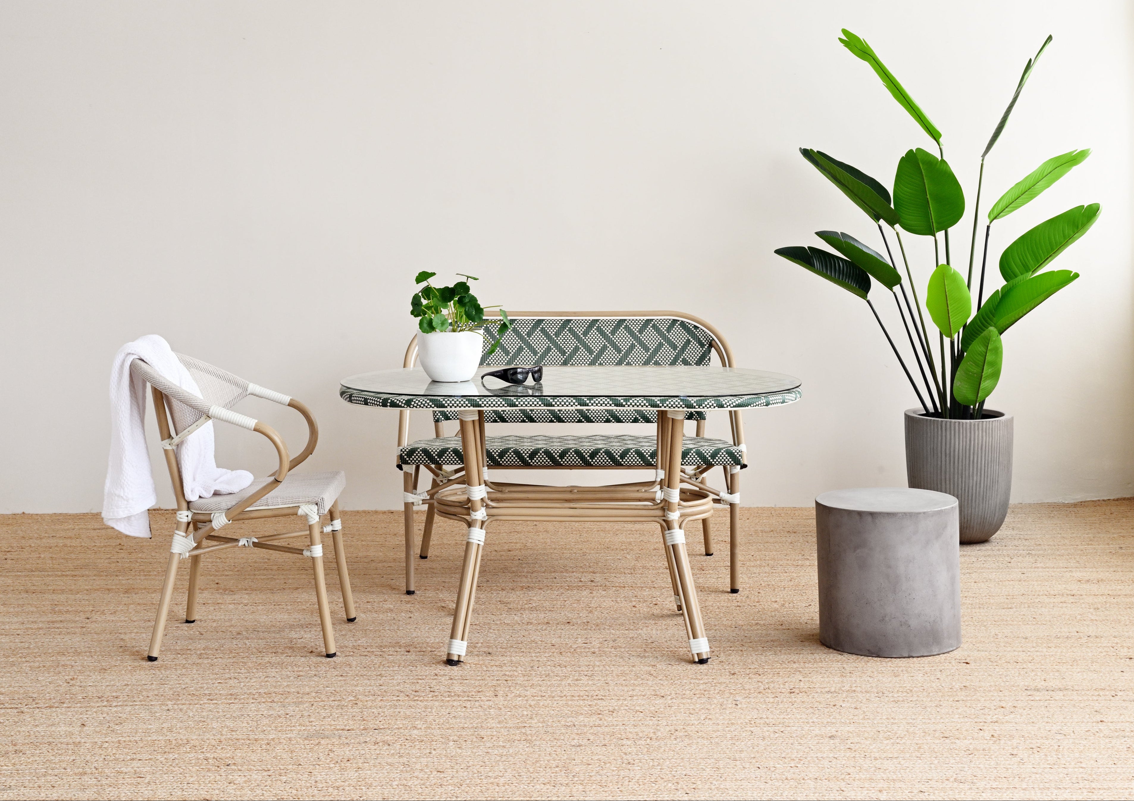 Modern indoor setting with a round glass table, chairs, and potted plants on a wooden floor.