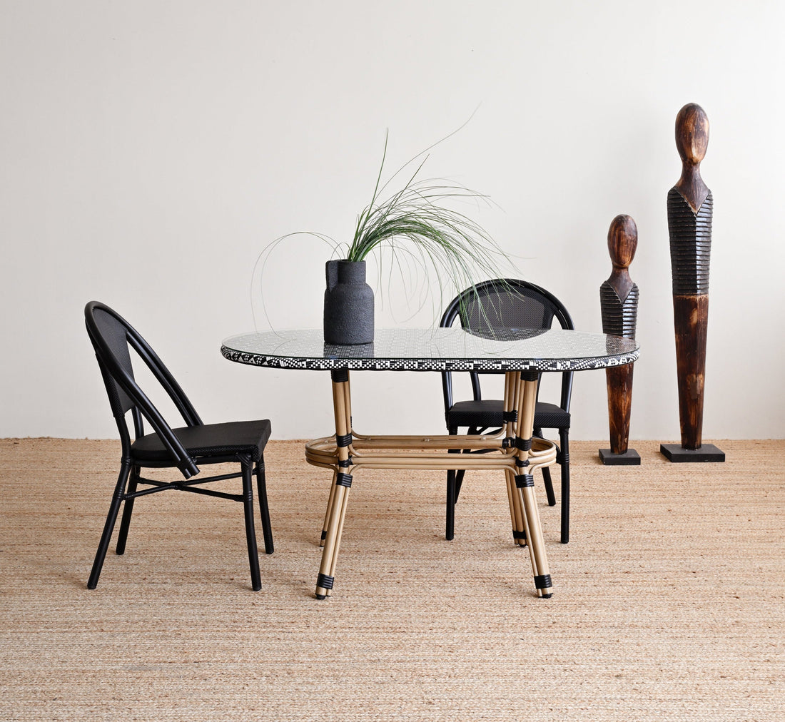 Dining area with a marble table, black chairs, and decorative vases against a white wall.