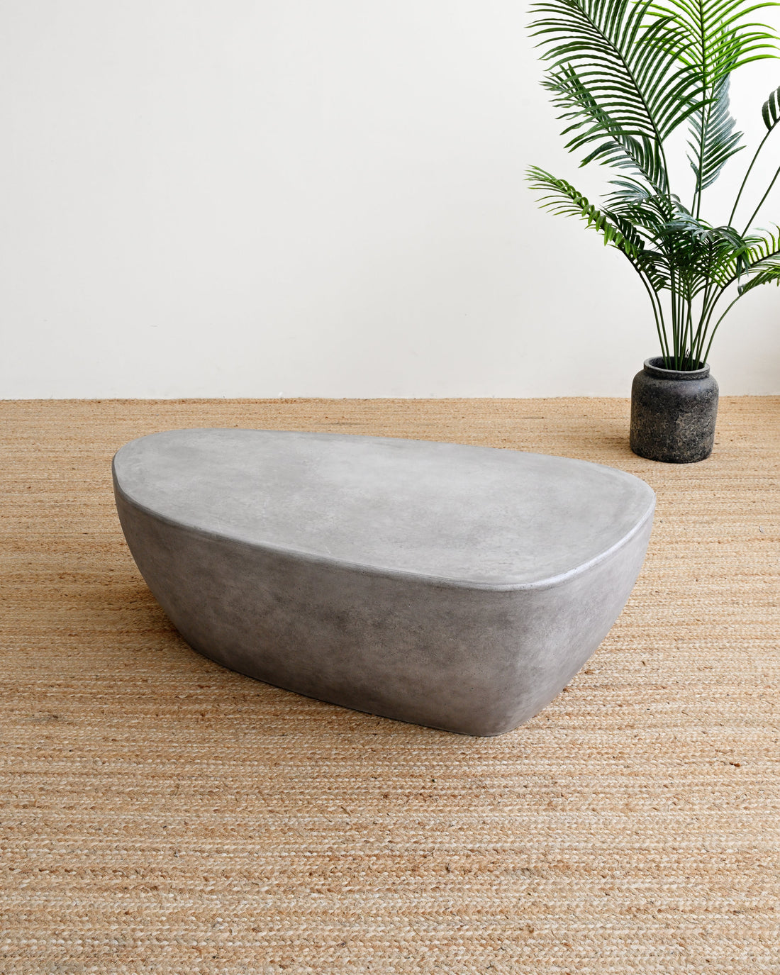 Concrete planter on a wooden floor with a plant in the background
