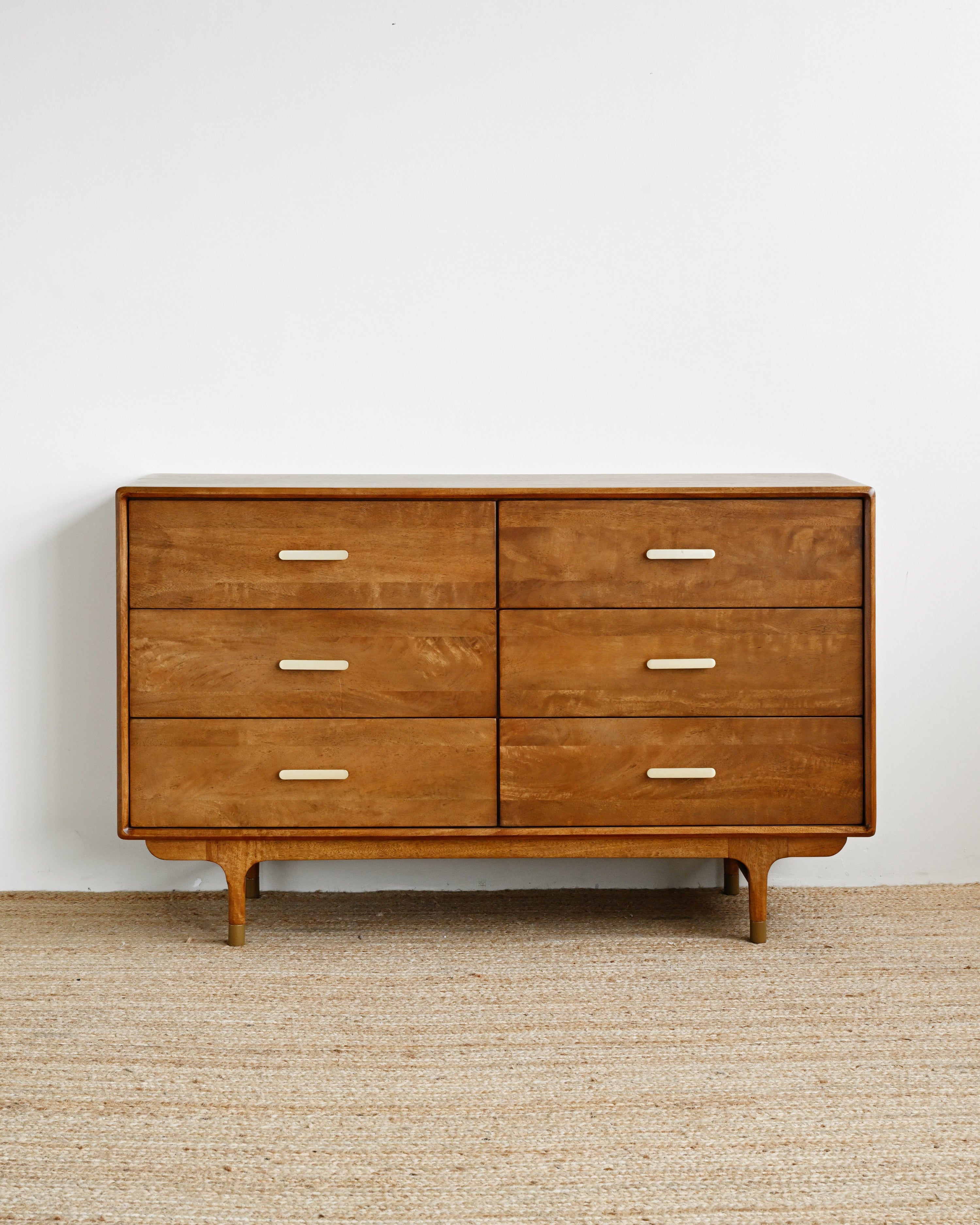 Wooden dresser with six drawers on a beige carpet against a white wall