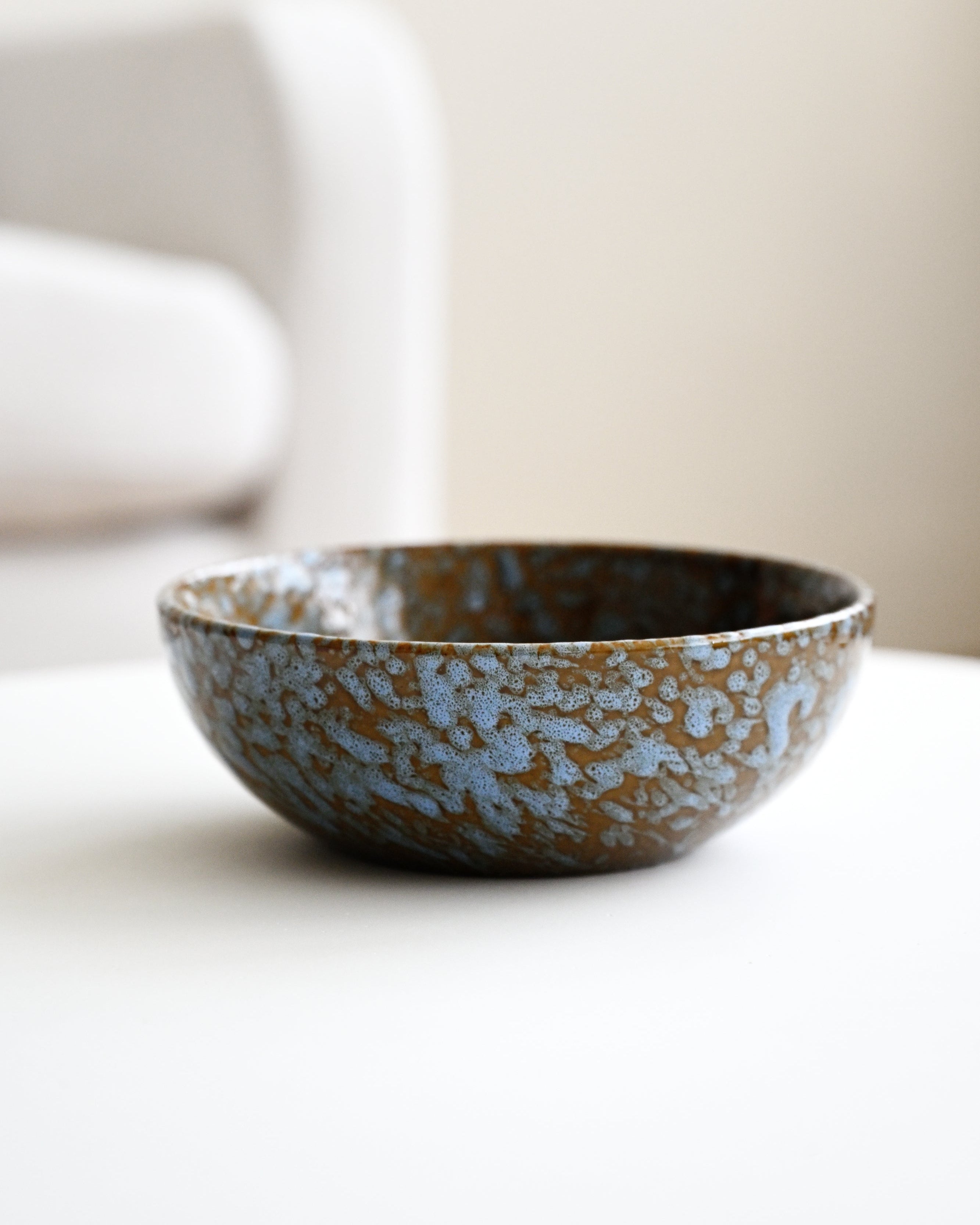 Ceramic bowl with blue speckled pattern on a white surface